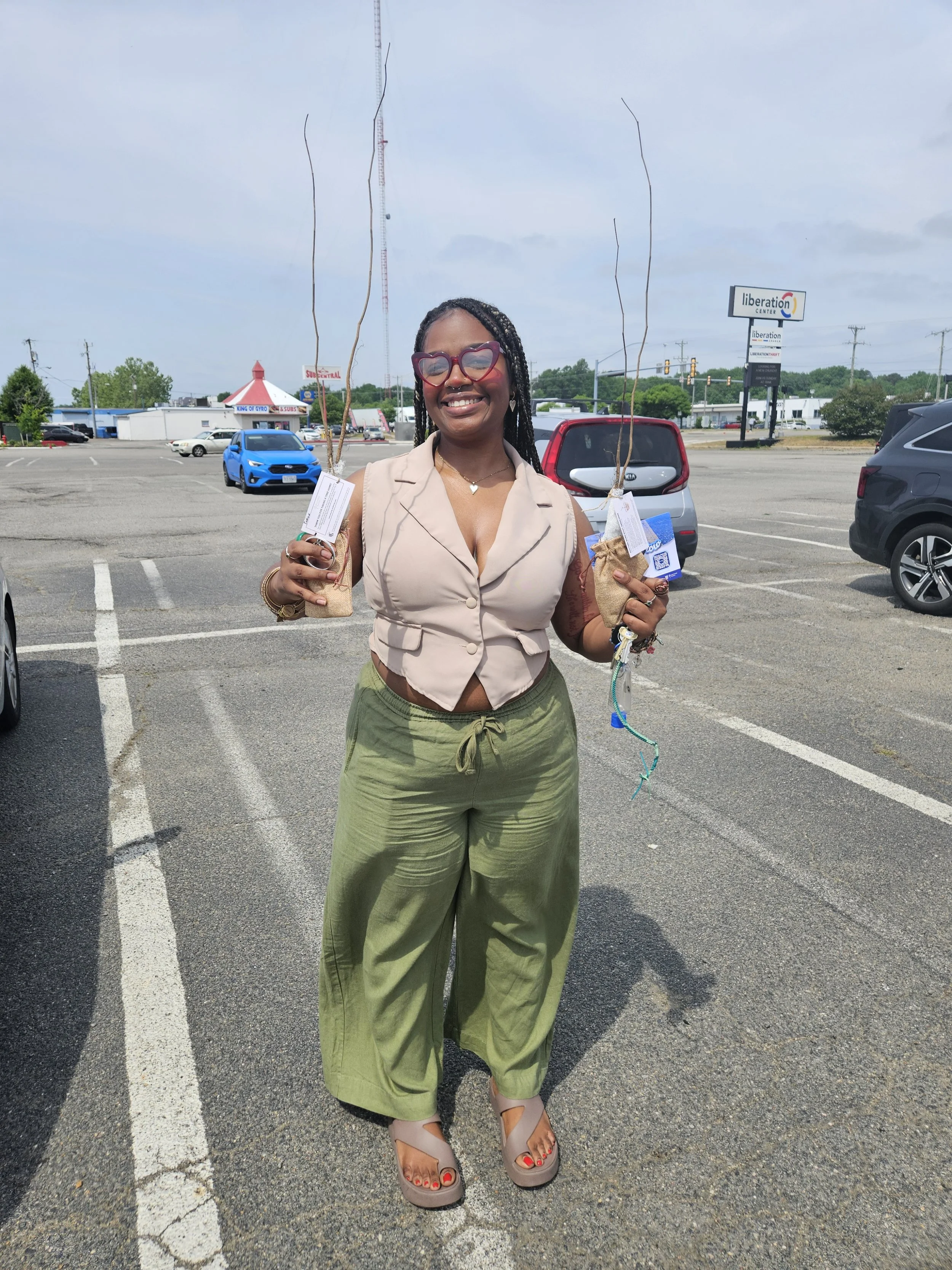 Photo of a Tayia West posing with the saplings she took home from the giveaway.