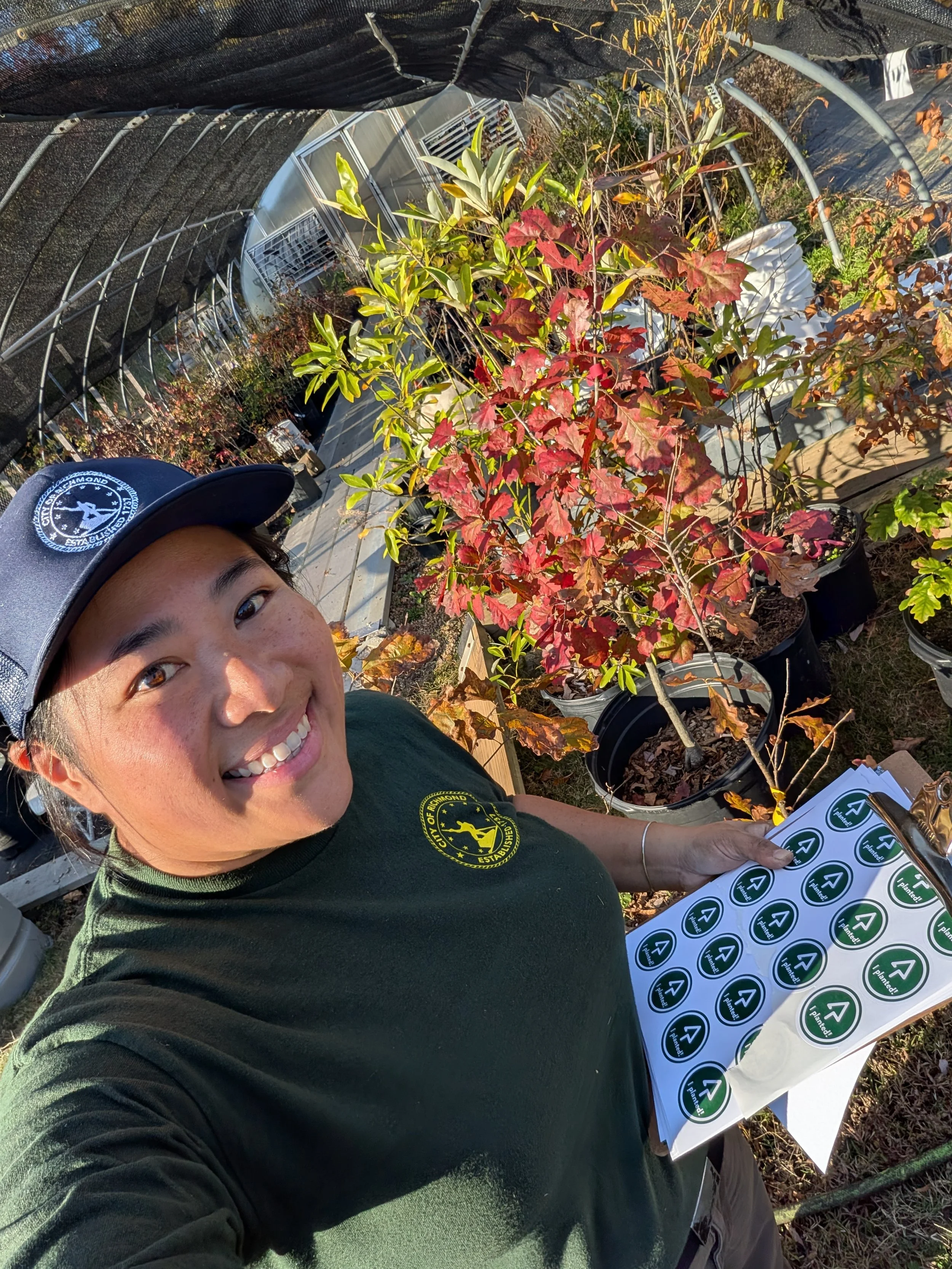 Qui with young potted trees and Richmond Tree Week’s famous “I planted!” stickers with the Reforest Richmond logo.