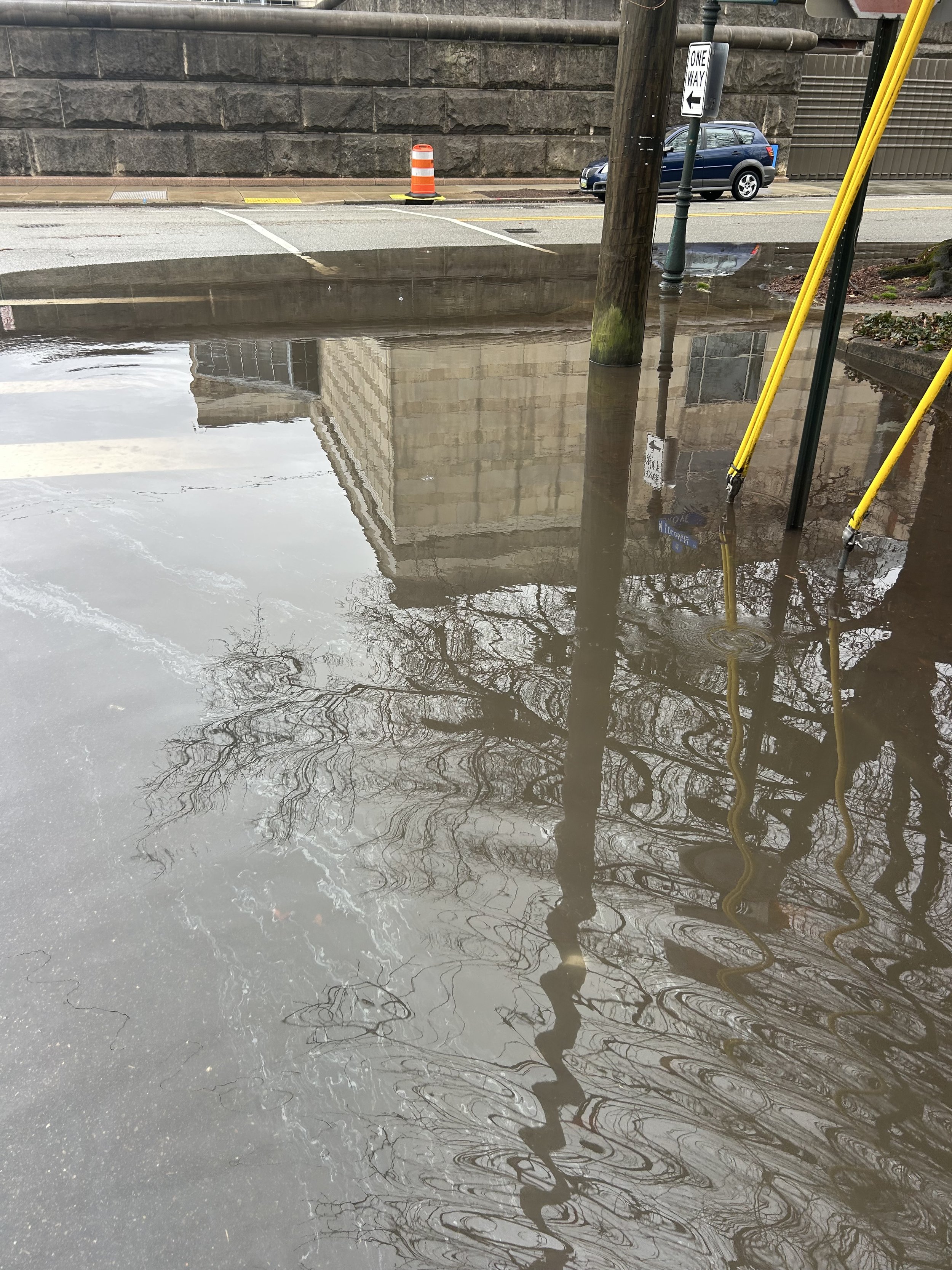 Photo of significant flooding after rainfall in Richmond that is covering a roadway and sidewalk at an intersection. The puddle is large enough that is spans the entirety of the bottom 90% of the photo.