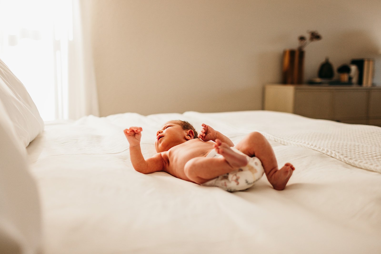 newborn-baby-stretching-on-white-bed.jpg
