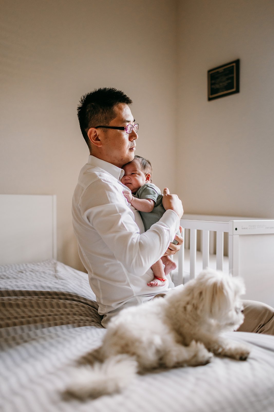 new-dad-with-dog-and newborn-bedroom-.jpg