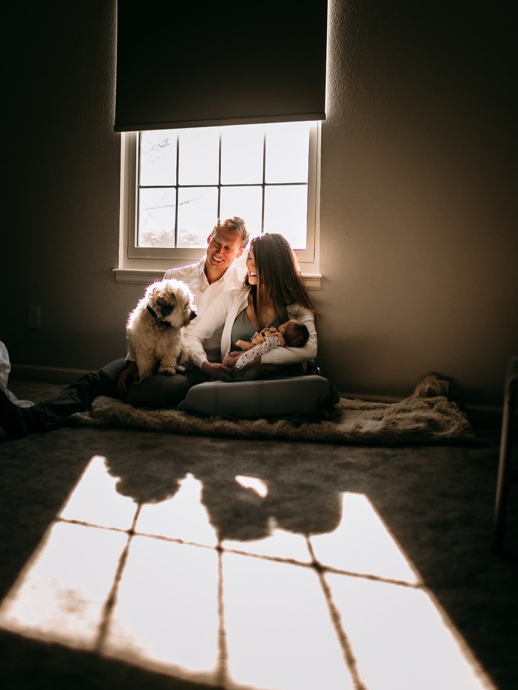 new-parents-sitting-in-light-with-baby-and-puppy.jpg