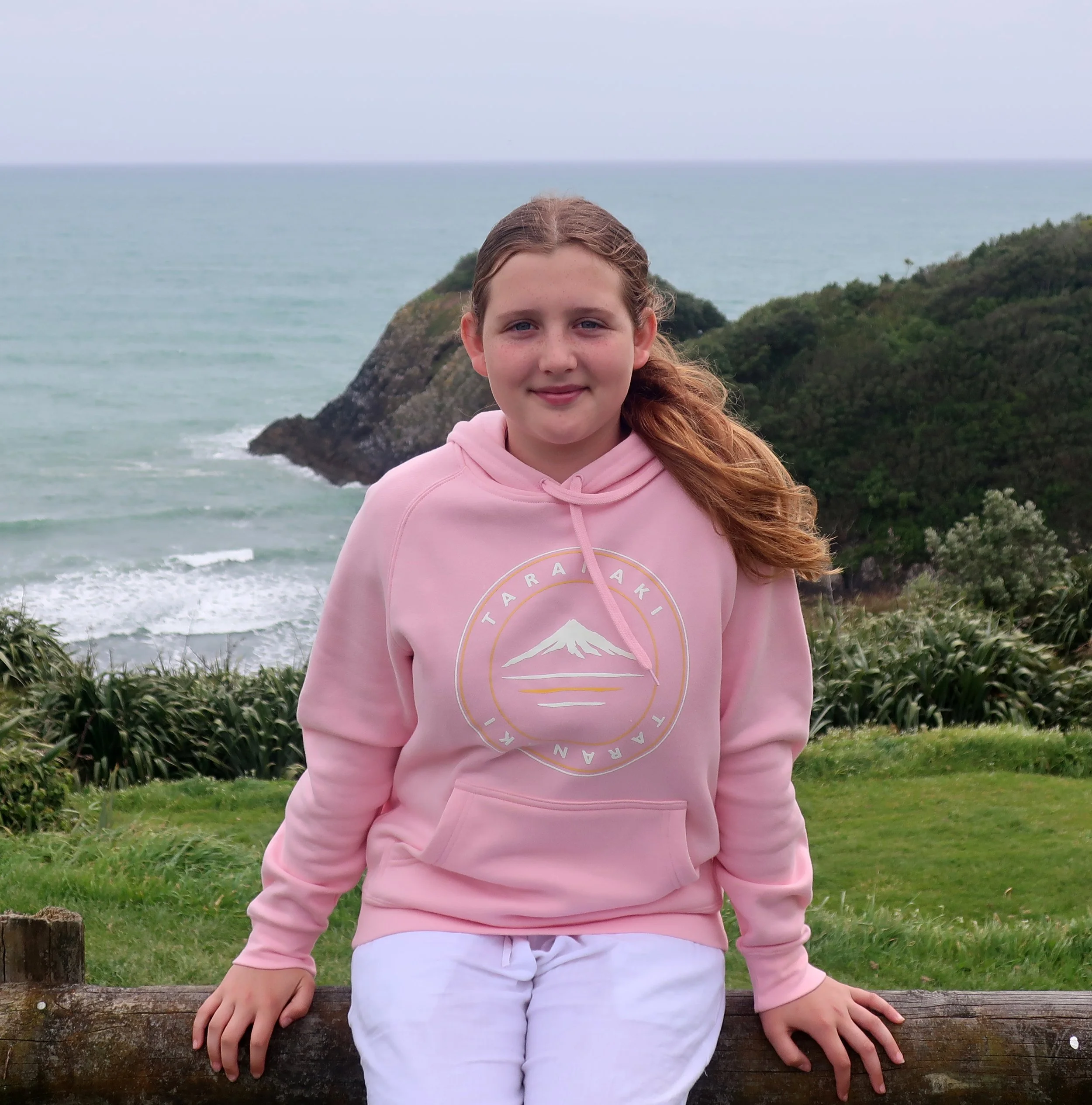 Young girl pictured wearing a pink hoody with the Provincial Taranaki Mountain Logo on front chest.