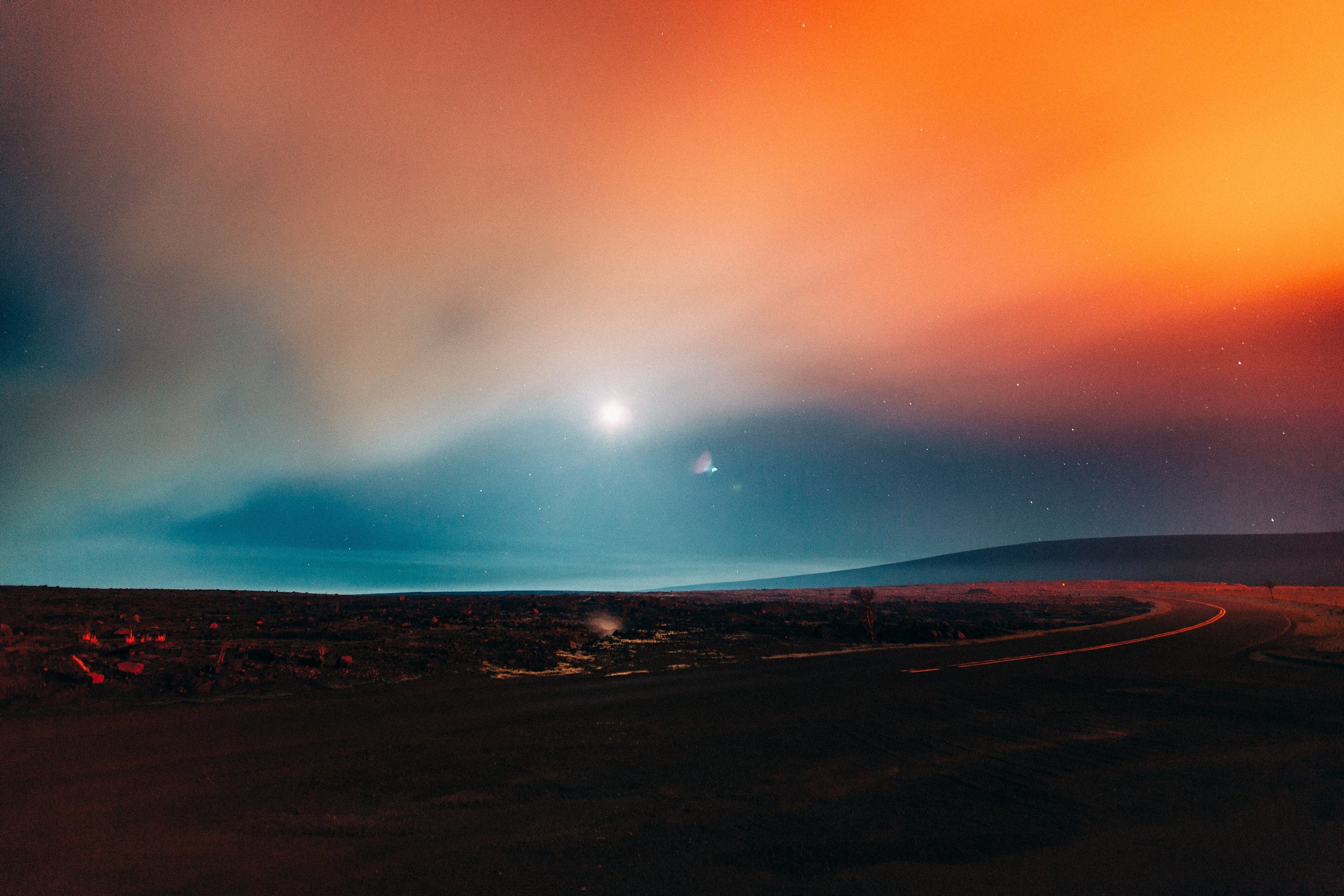 Moonlit volcanic haze above a dark Big Island landscape with coral, orange, and turquoise sky