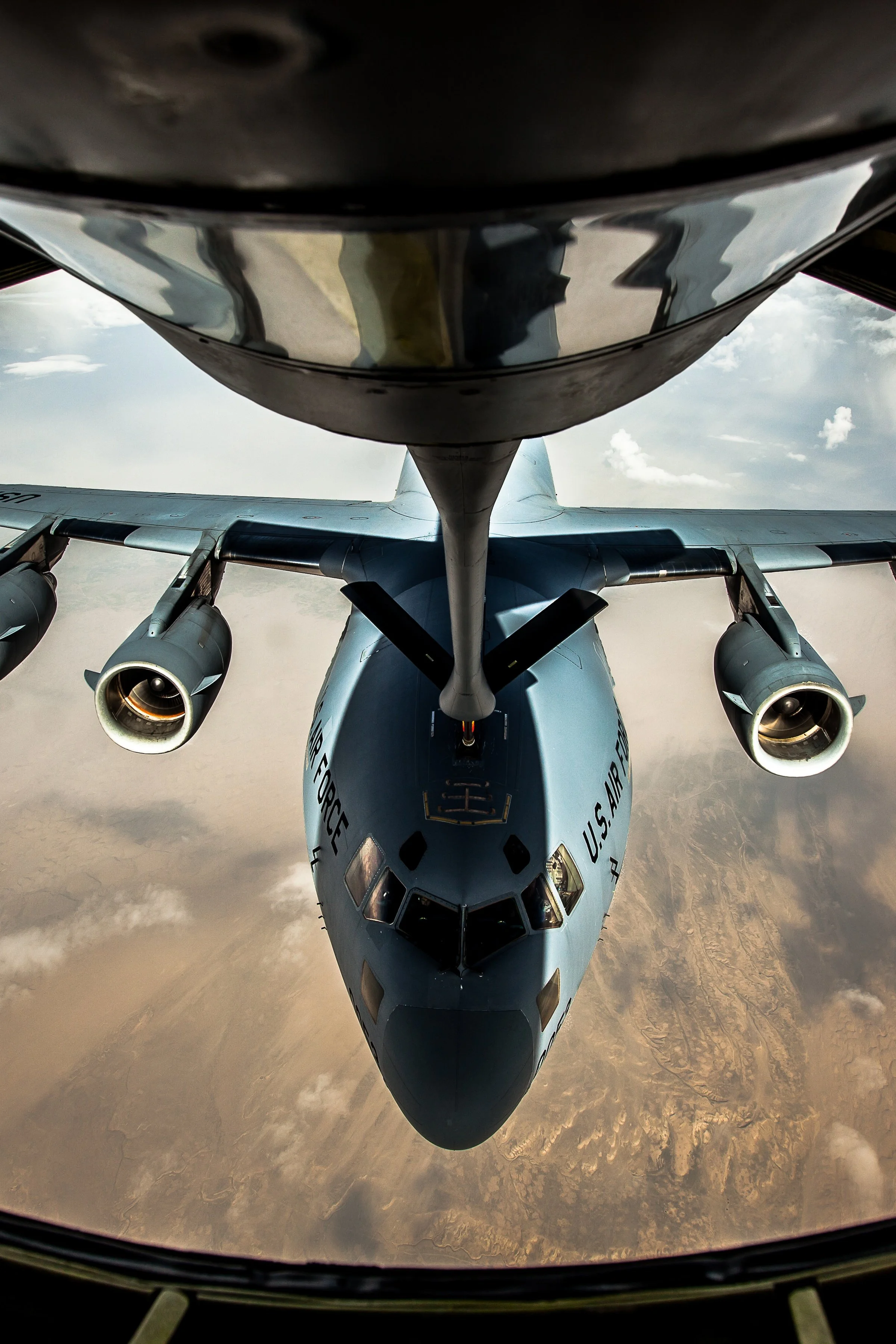 Vertical detail of the aircraft nose, engines, wings, and refueling boom centered in flight