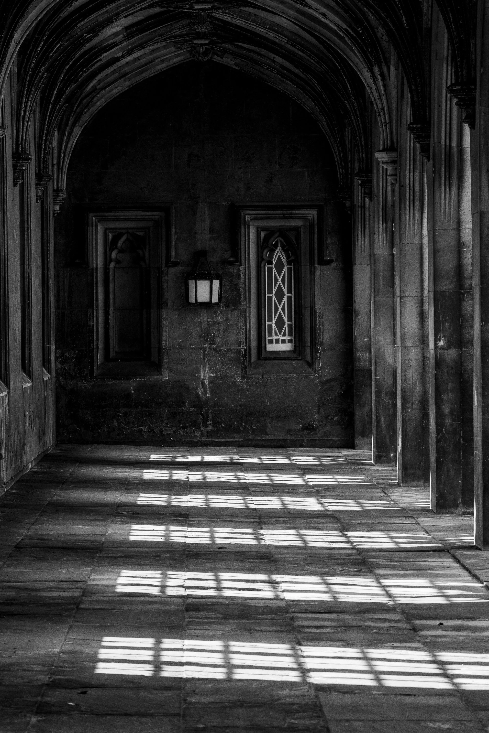 Closer view of the vaulted corridor, stone columns, shadowed doorway, and patterned light