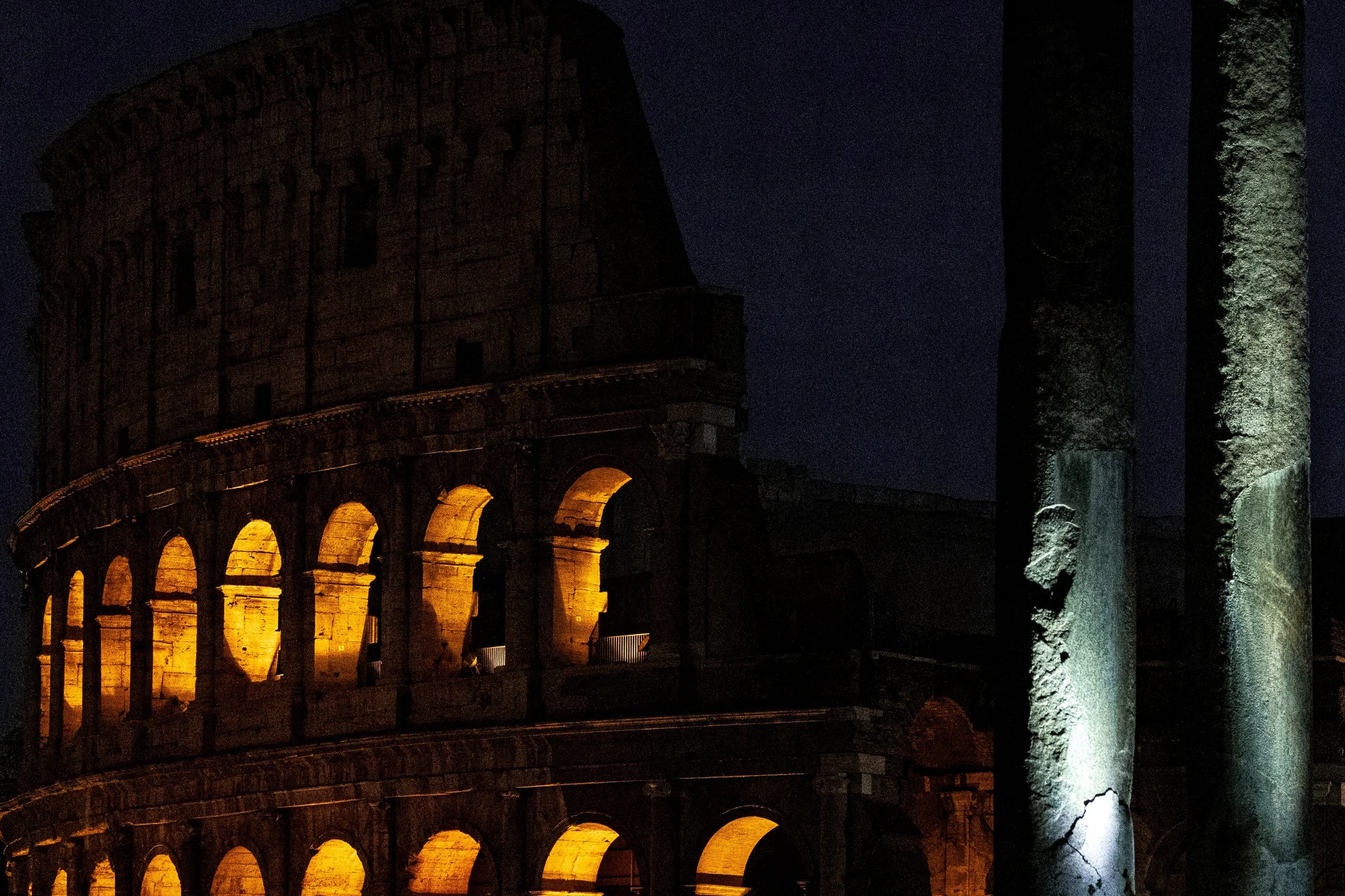 Close detail of warm Colosseum stone, repeating arches, columns, and carved capitals