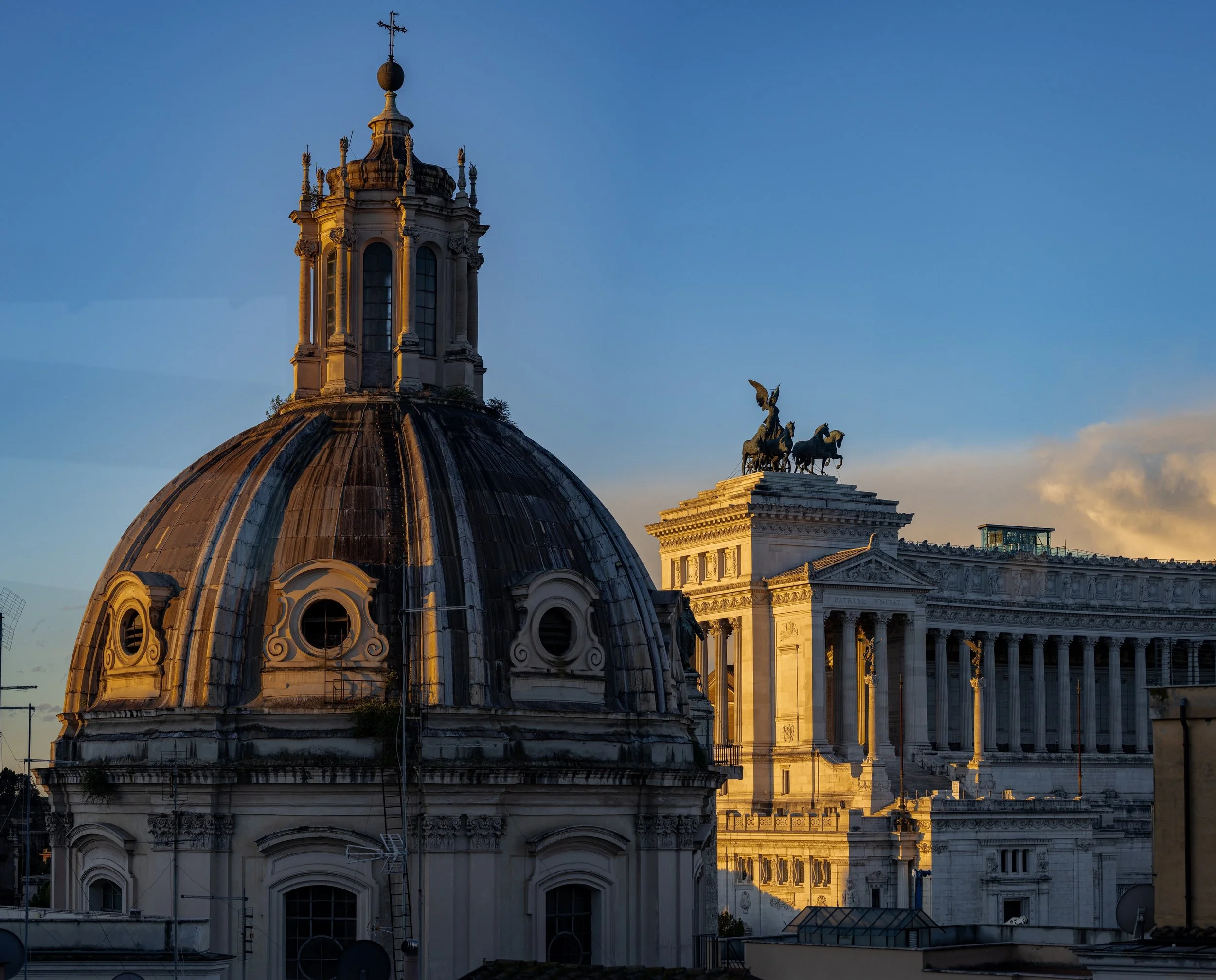 Sunlit Roman dome with circular windows and a winged quadriga rising in the distance