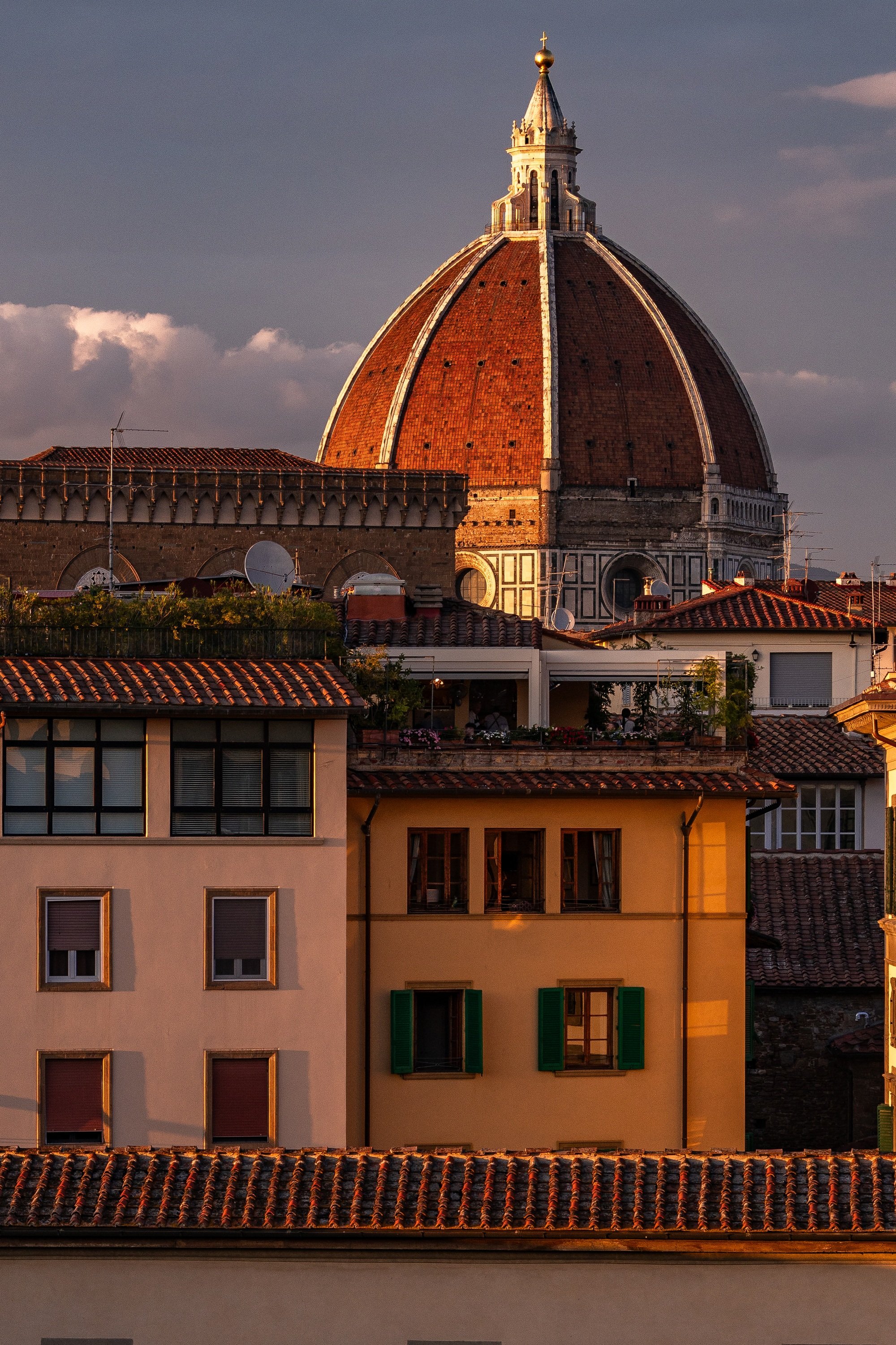 Close view of the red Duomo, bell tower, tiled roofs, shutters, and sunlit Florentine facades