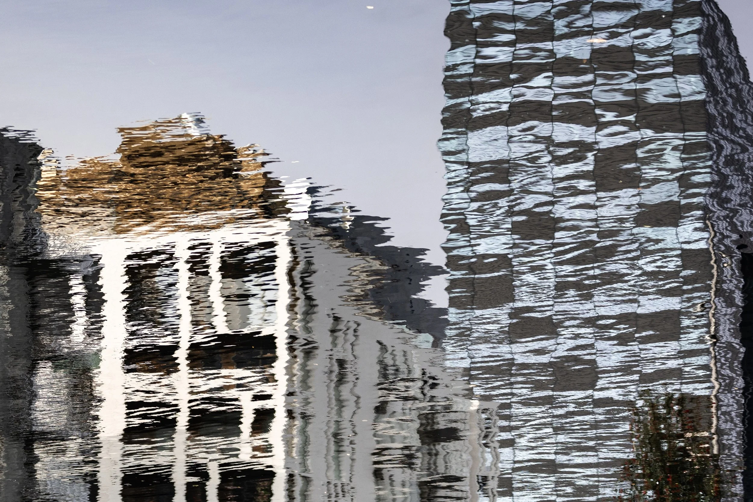 Close detail of windows and vertical building forms stretched by moving water