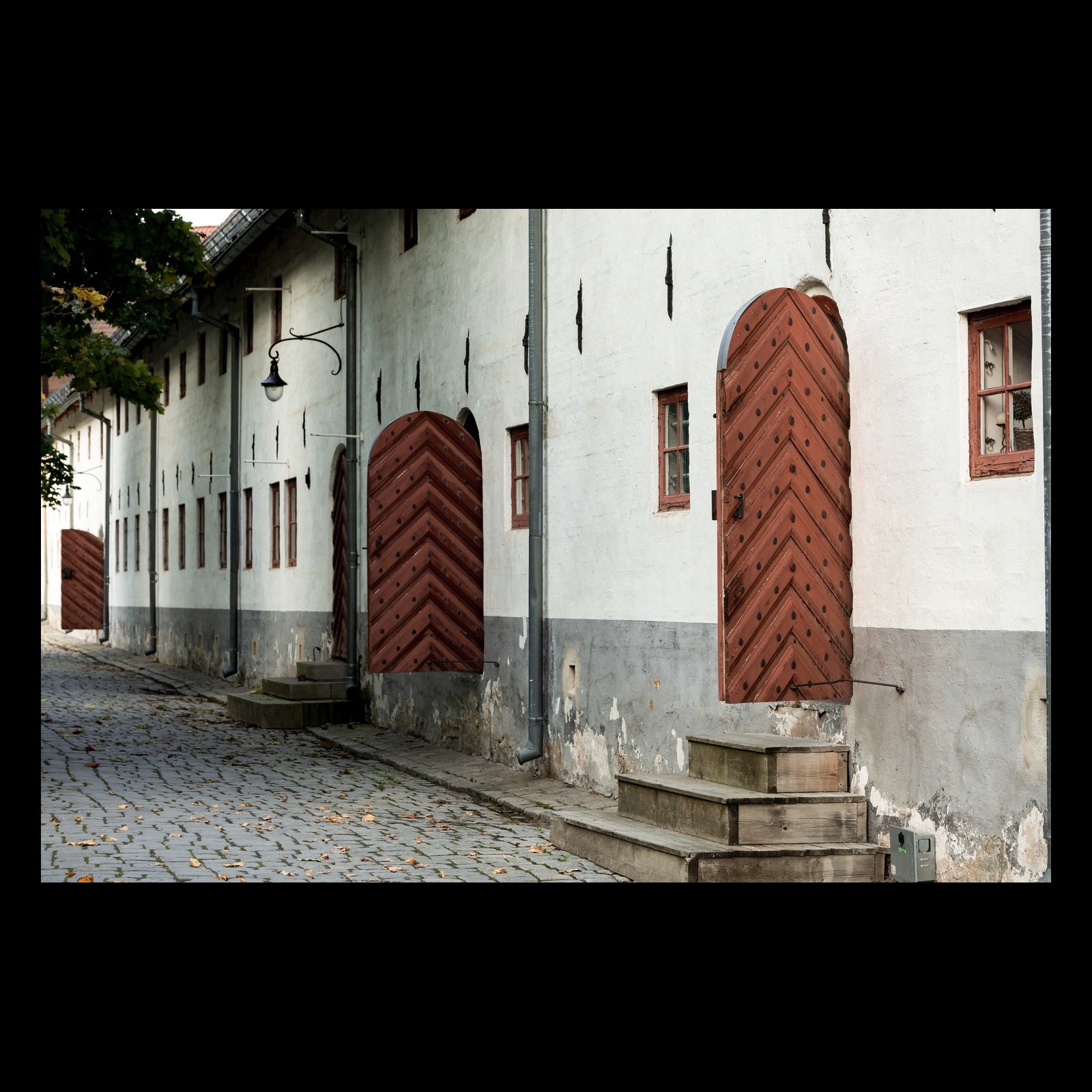 Akershus Fortress photograph of red doors along a white wall, presented in full against a black background