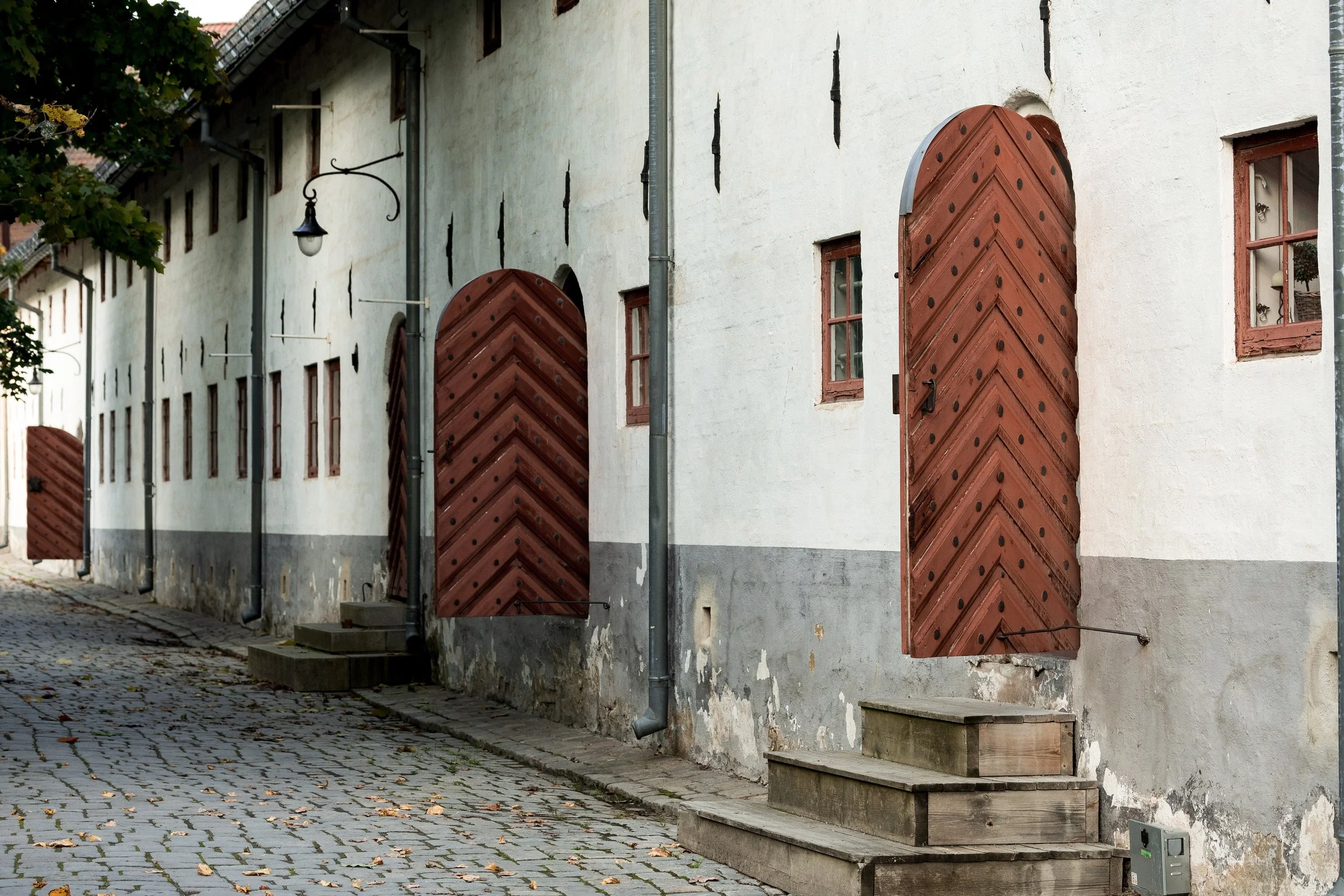 Three red chevron-patterned wooden doors beside a cobblestone lane at Akershus Fortress in Oslo