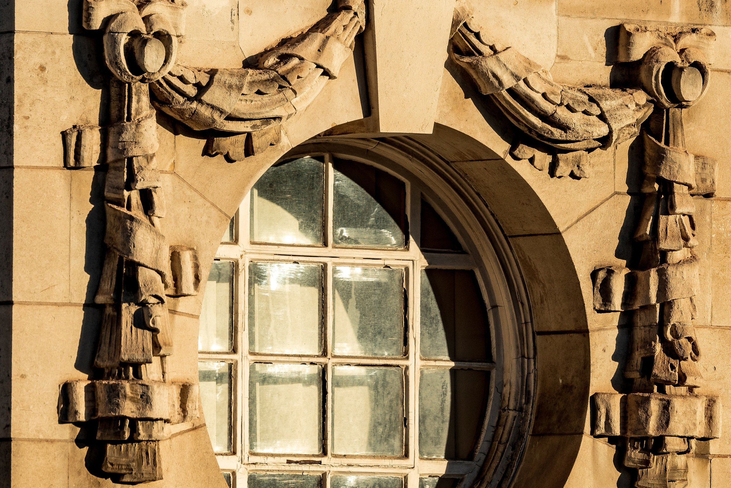 Close detail of the round window, layered stone surround, and carved figures on both sides
