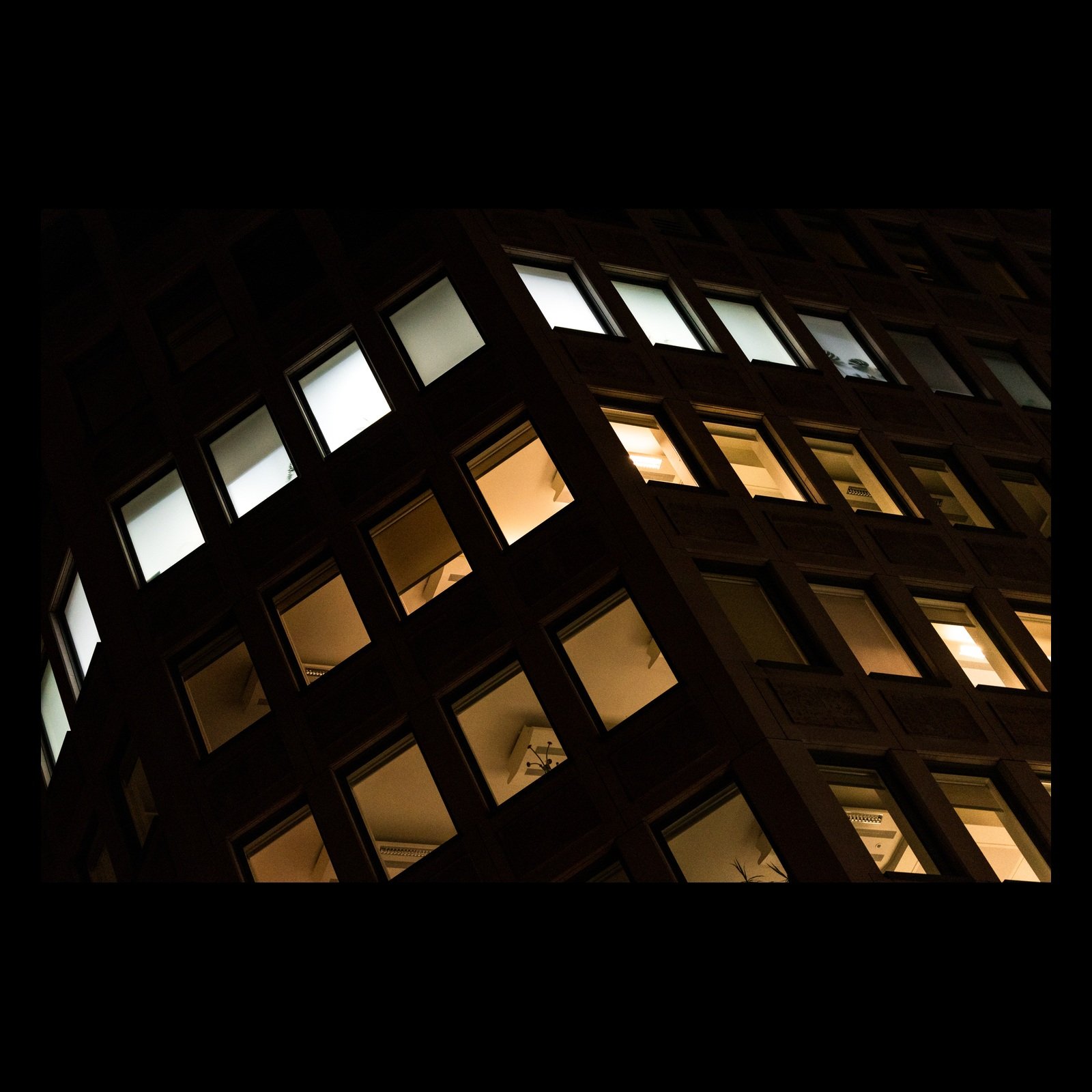 After Hours photograph of illuminated office windows at night, presented in full against a black background