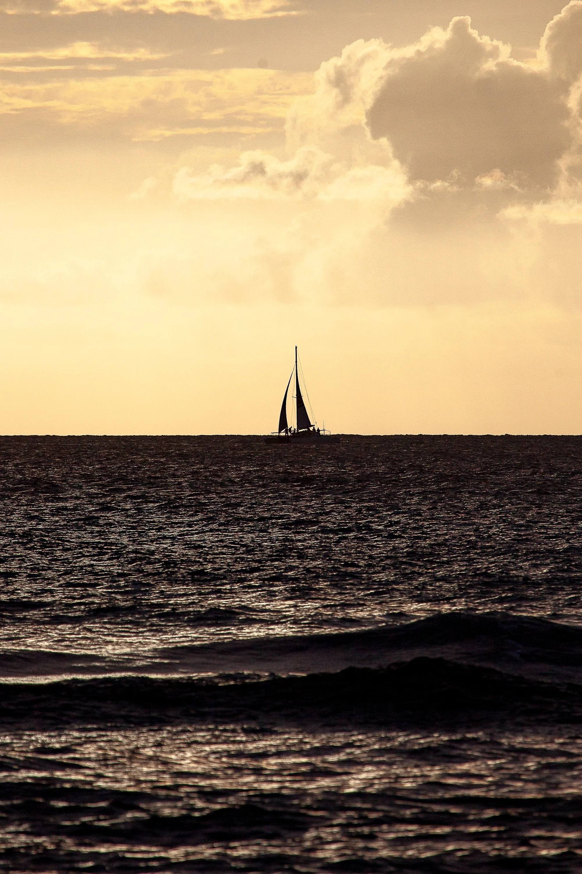 Detail crop of the sailboat and horizon beneath golden clouds in Follow the Golden Passage.