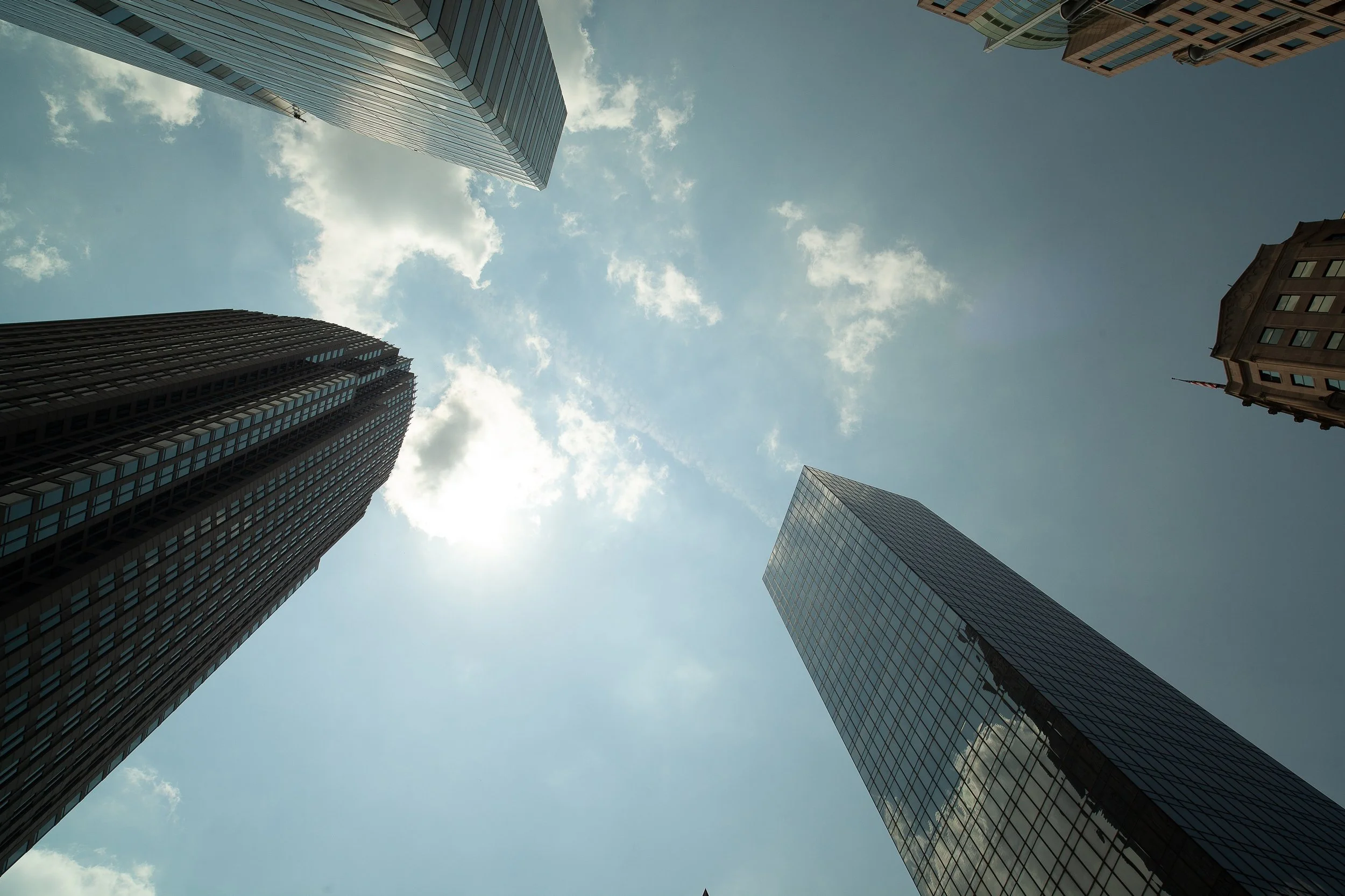 Complete uncropped artwork for Vertical Weather, showing tall city buildings rise from every edge toward a bright opening of sky