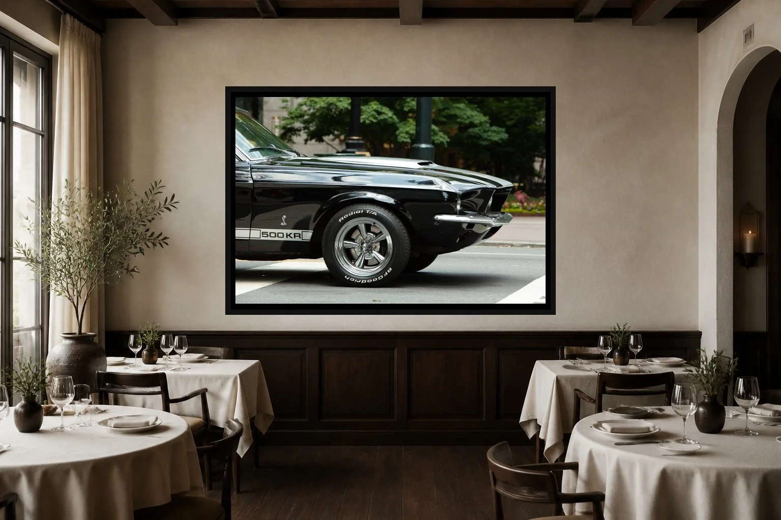 Five Hundred Horses displayed in a black frame within an intimate fine-dining room with plaster walls, dark wood, linen tables, no guests, and a clear central wall