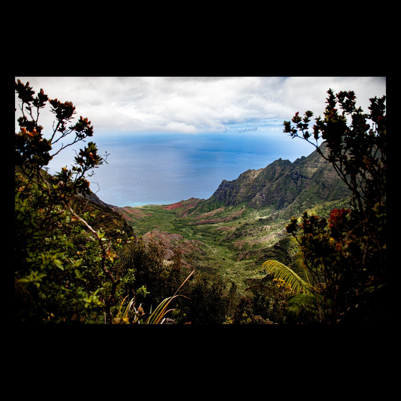 Full-frame black presentation thumbnail of Valley to the Sea, showing a green valley descends between steep ridges toward a calm blue ocean