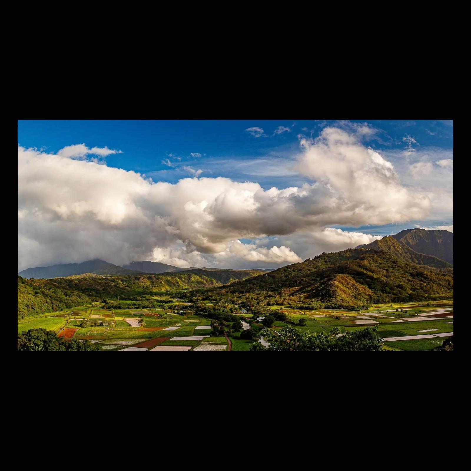 Full-frame black presentation thumbnail of Weather Over the Fields, showing heavy white clouds gather above a patchwork of fields and low mountain ridges