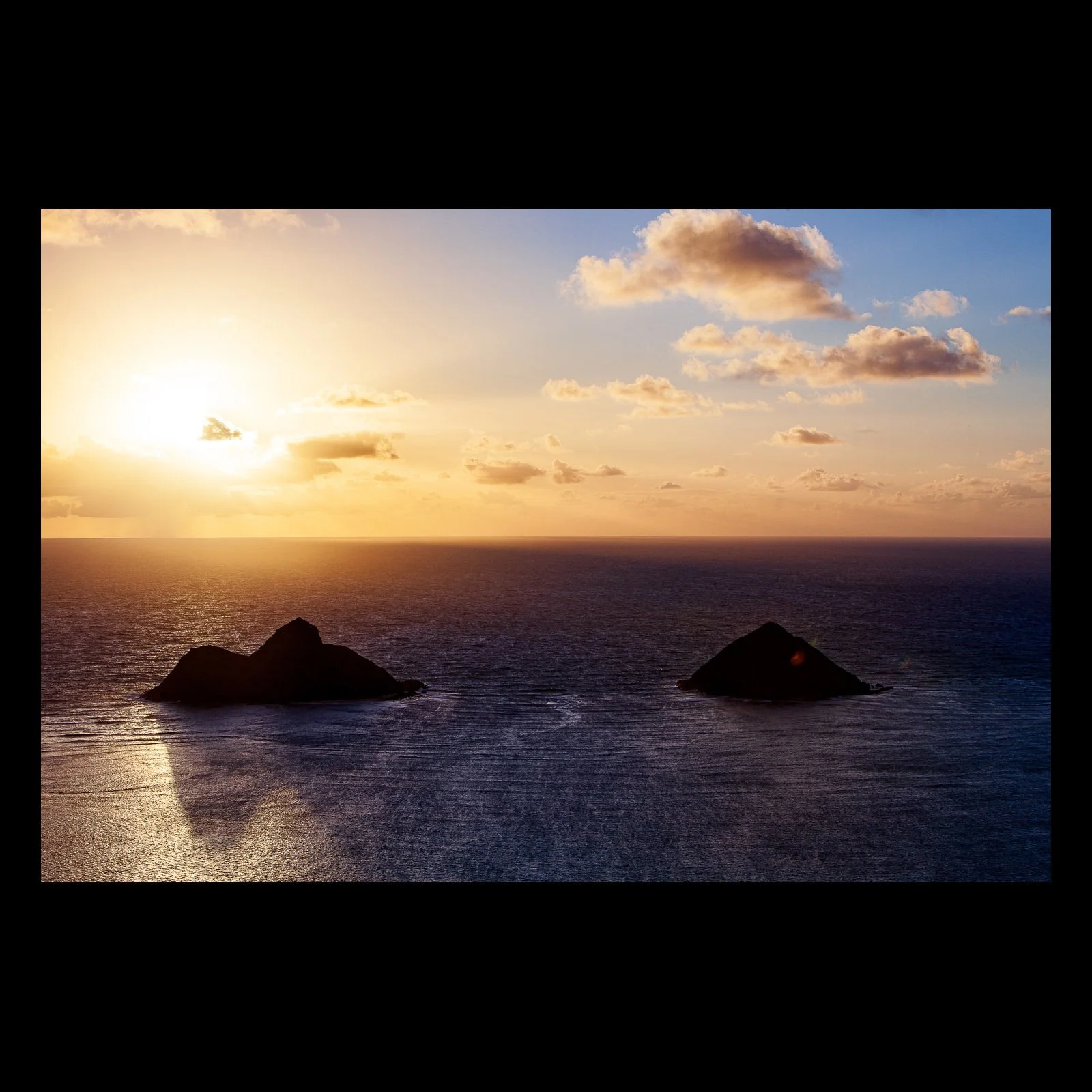Full-frame black presentation thumbnail of Twin Islands at Dusk, showing two dark offshore islands divide a warm sunset reflected across calm water