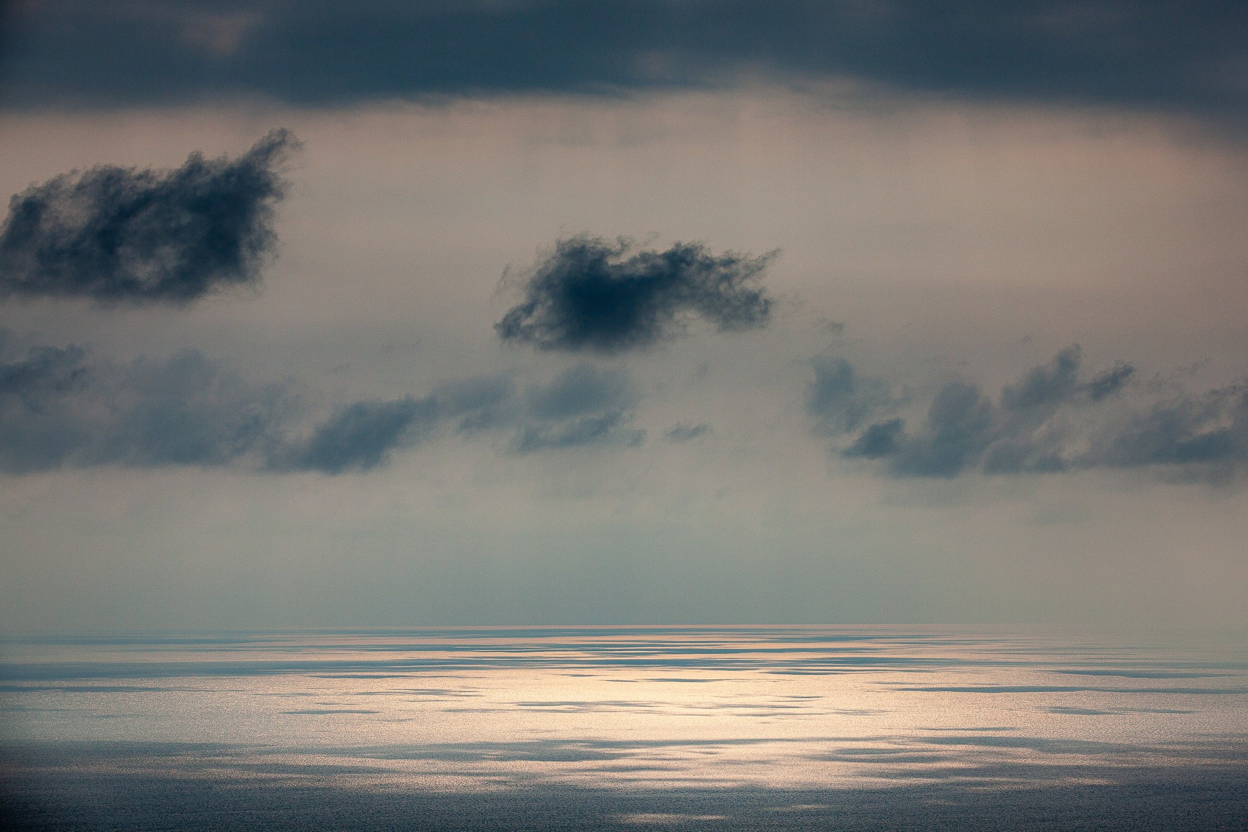 Complete uncropped artwork for Silver Water, showing a pale opening in the clouds reflects as a silver band across a subdued ocean