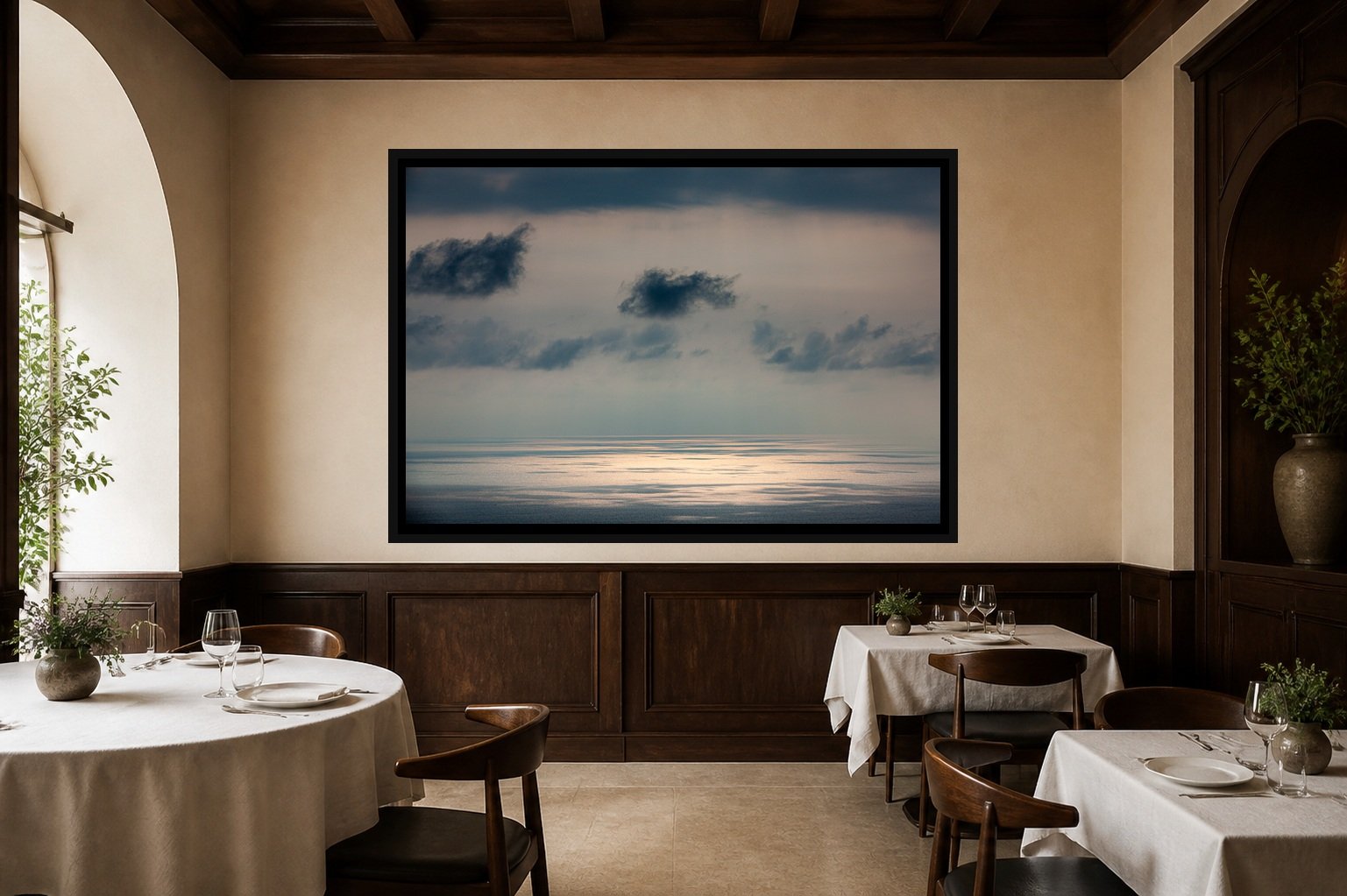 Silver Water displayed in a black frame within an intimate fine-dining room with plaster walls, dark wood, linen tables, no guests, and a clear central wall