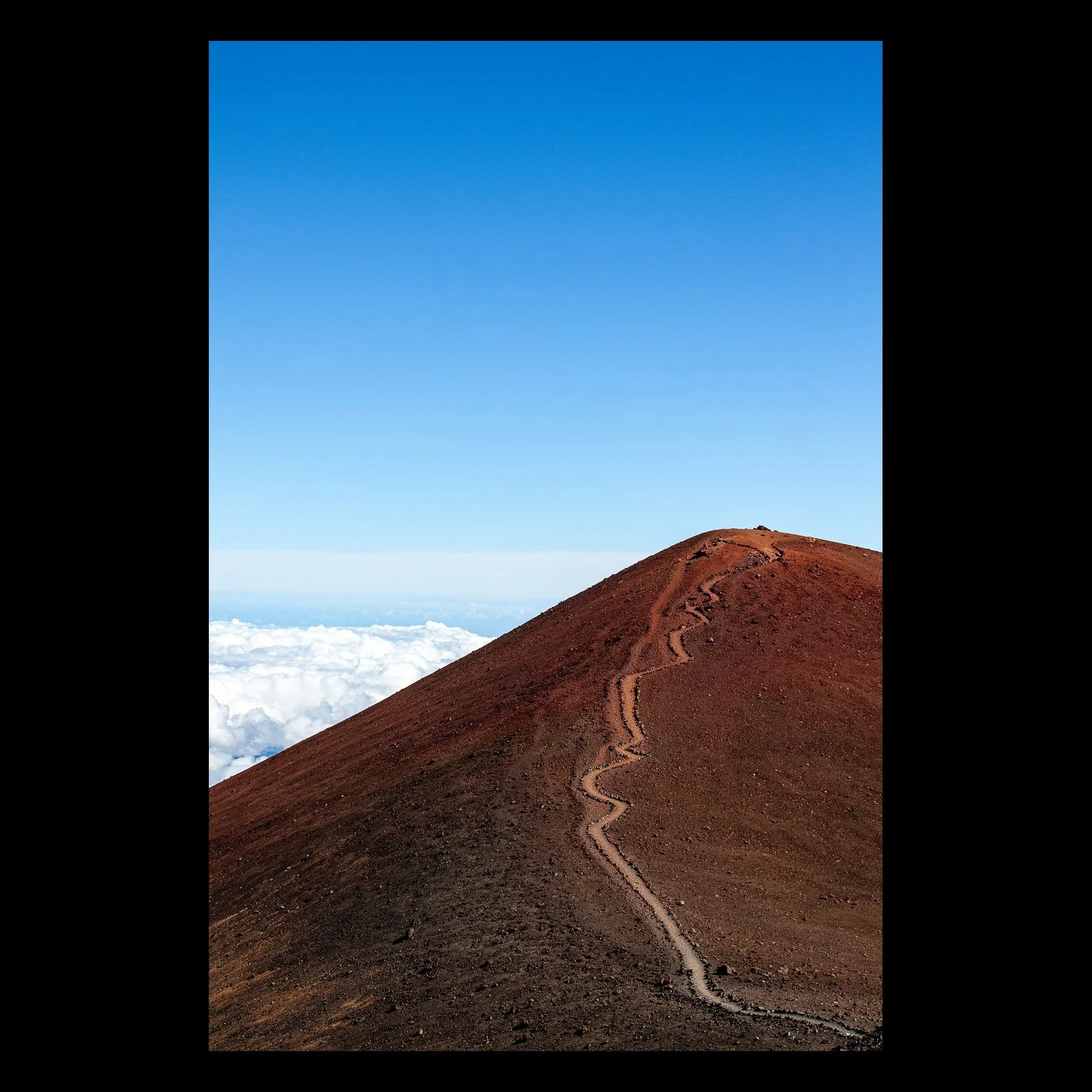 Full-frame black presentation thumbnail of Path Above the Clouds, showing a narrow trail climbs a red volcanic ridge above a white layer of clouds