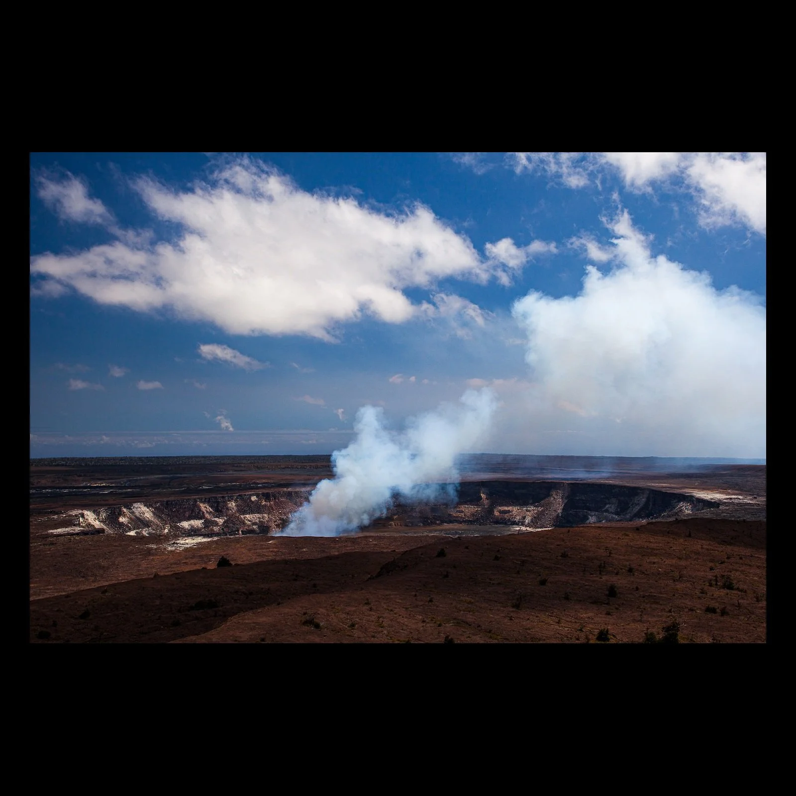 Full-frame black presentation thumbnail of Earth Breathing, showing white steam rises from a broad volcanic crater beneath bright clouds and blue sky