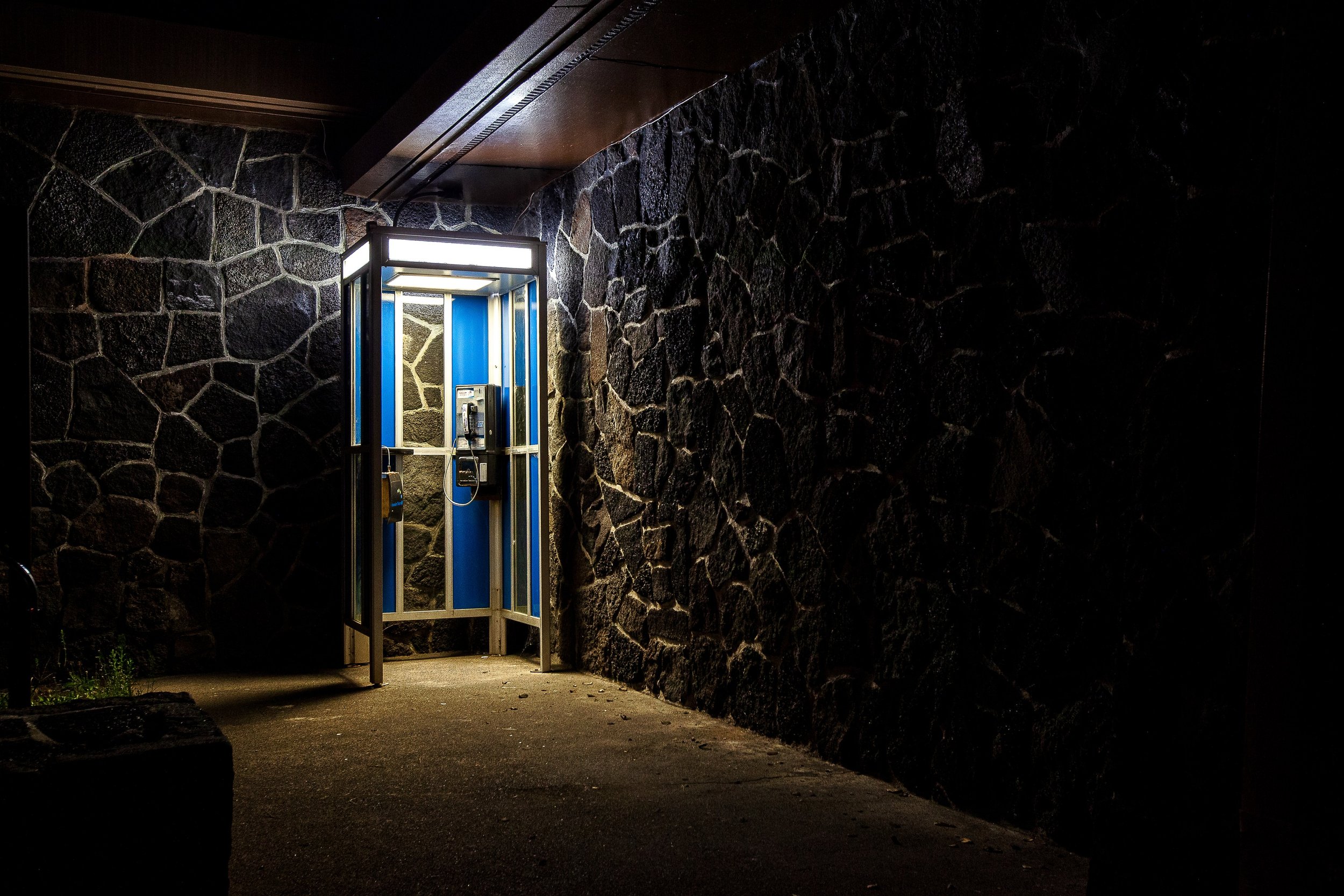 Complete uncropped artwork for Open After Dark, showing a bright glass doorway opens from a dark wall of rough volcanic stone