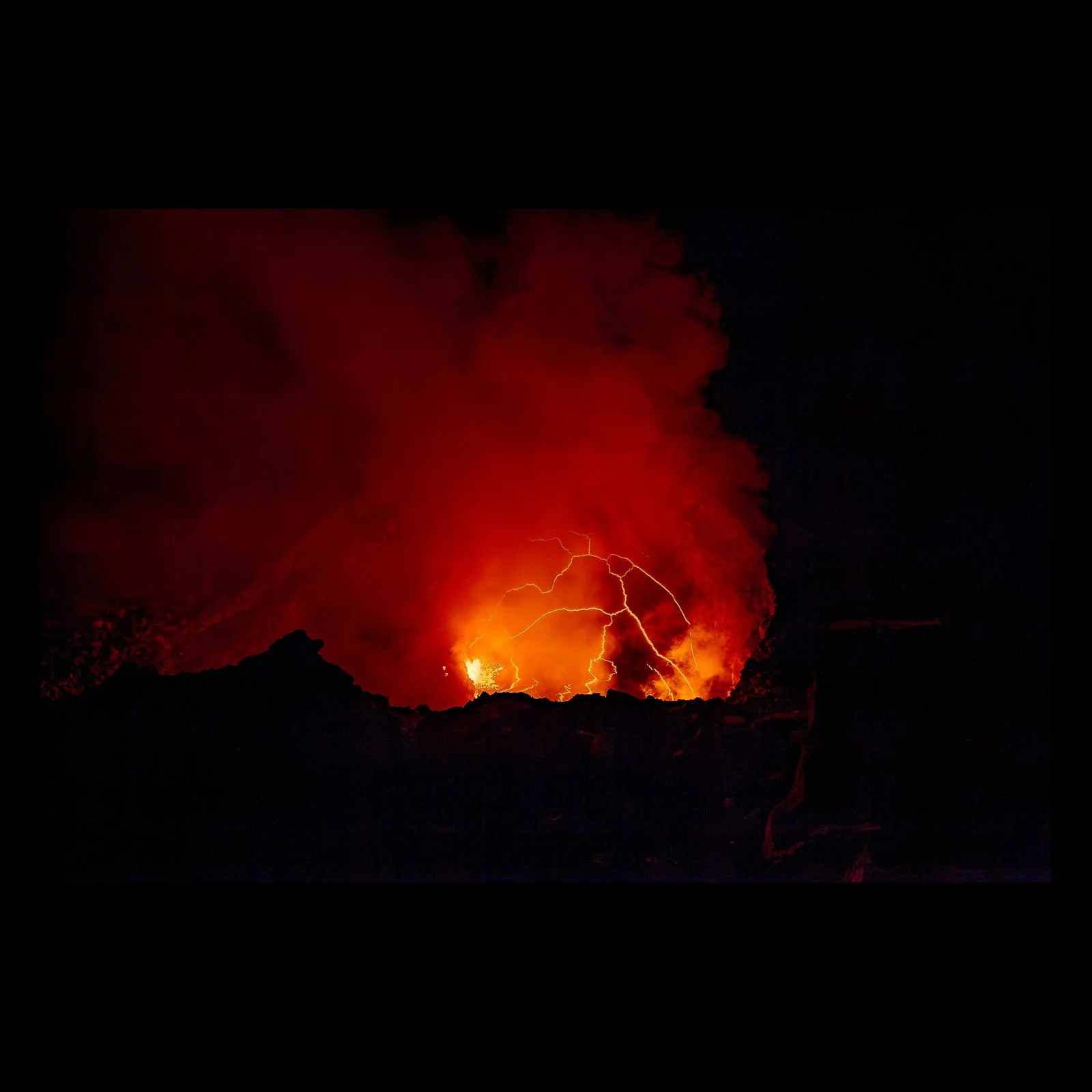 Full-frame black presentation thumbnail of Fire Writes Back, showing red volcanic light and branching lightning appear together beneath a dense black sky