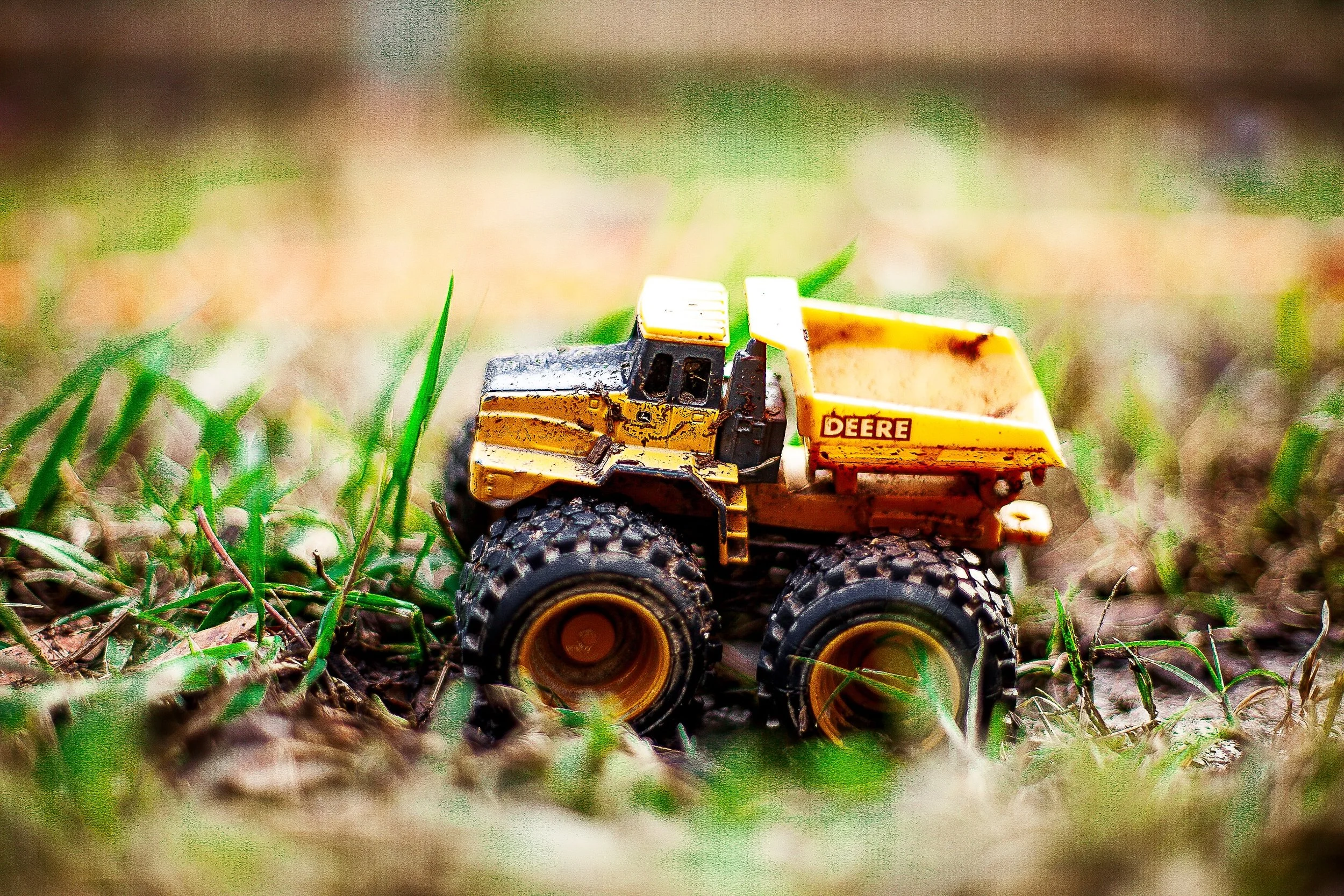 Complete uncropped artwork for Small Work, showing a small yellow toy loader sits among blades of grass at ground level