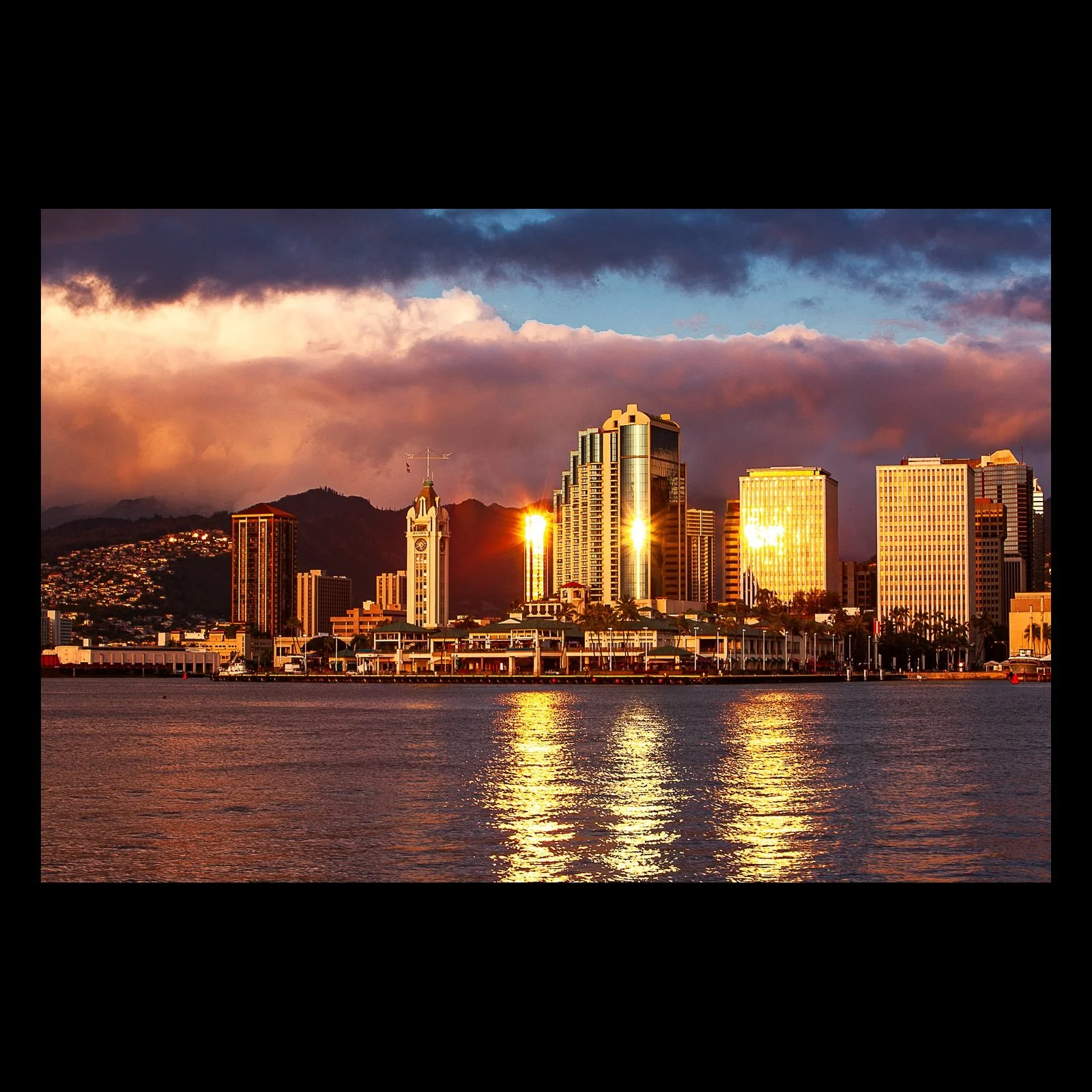 Full-frame black presentation thumbnail of Golden Waterfront, showing a waterfront skyline reflects orange late-day light across calm harbor water
