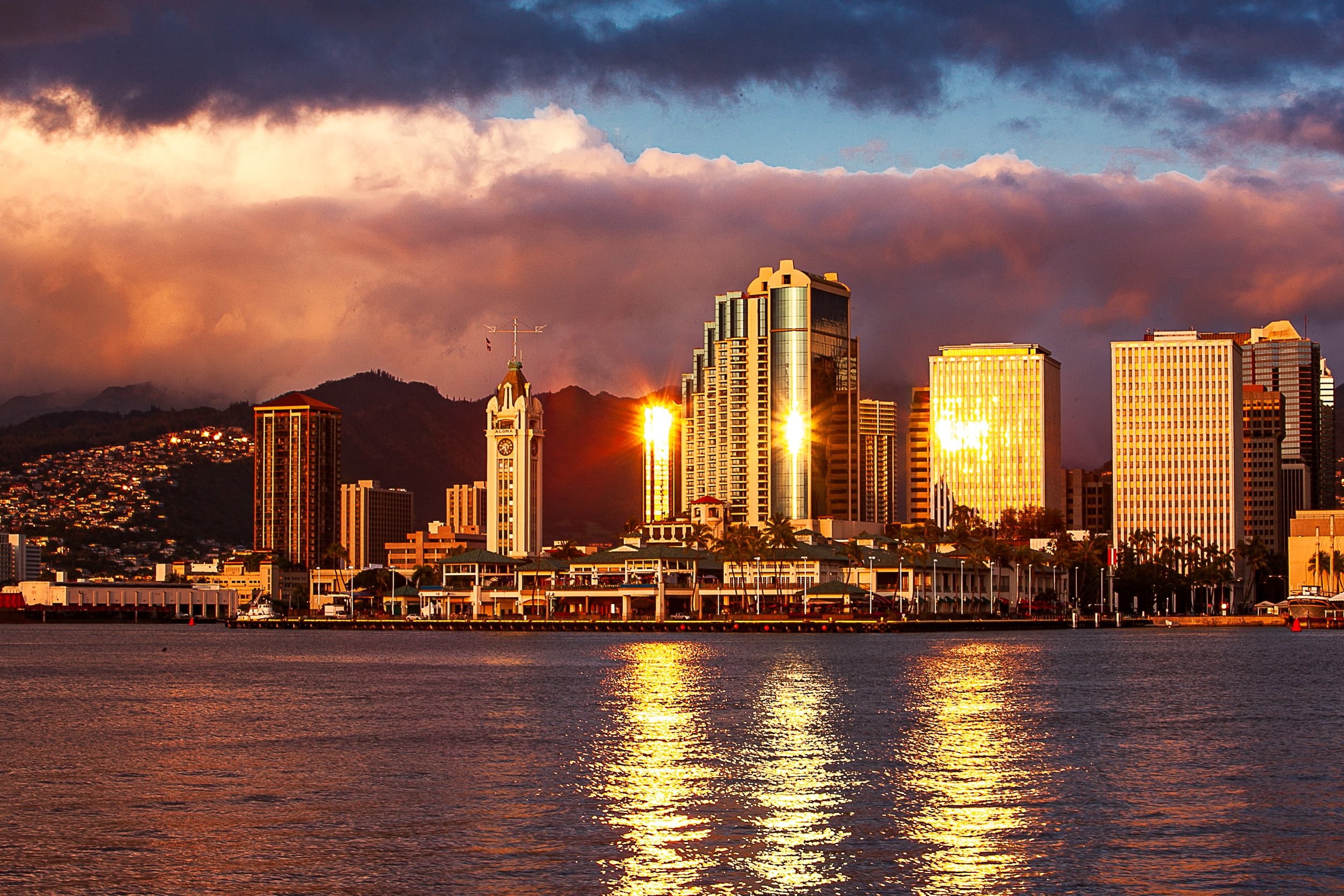 Complete uncropped artwork for Golden Waterfront, showing a waterfront skyline reflects orange late-day light across calm harbor water