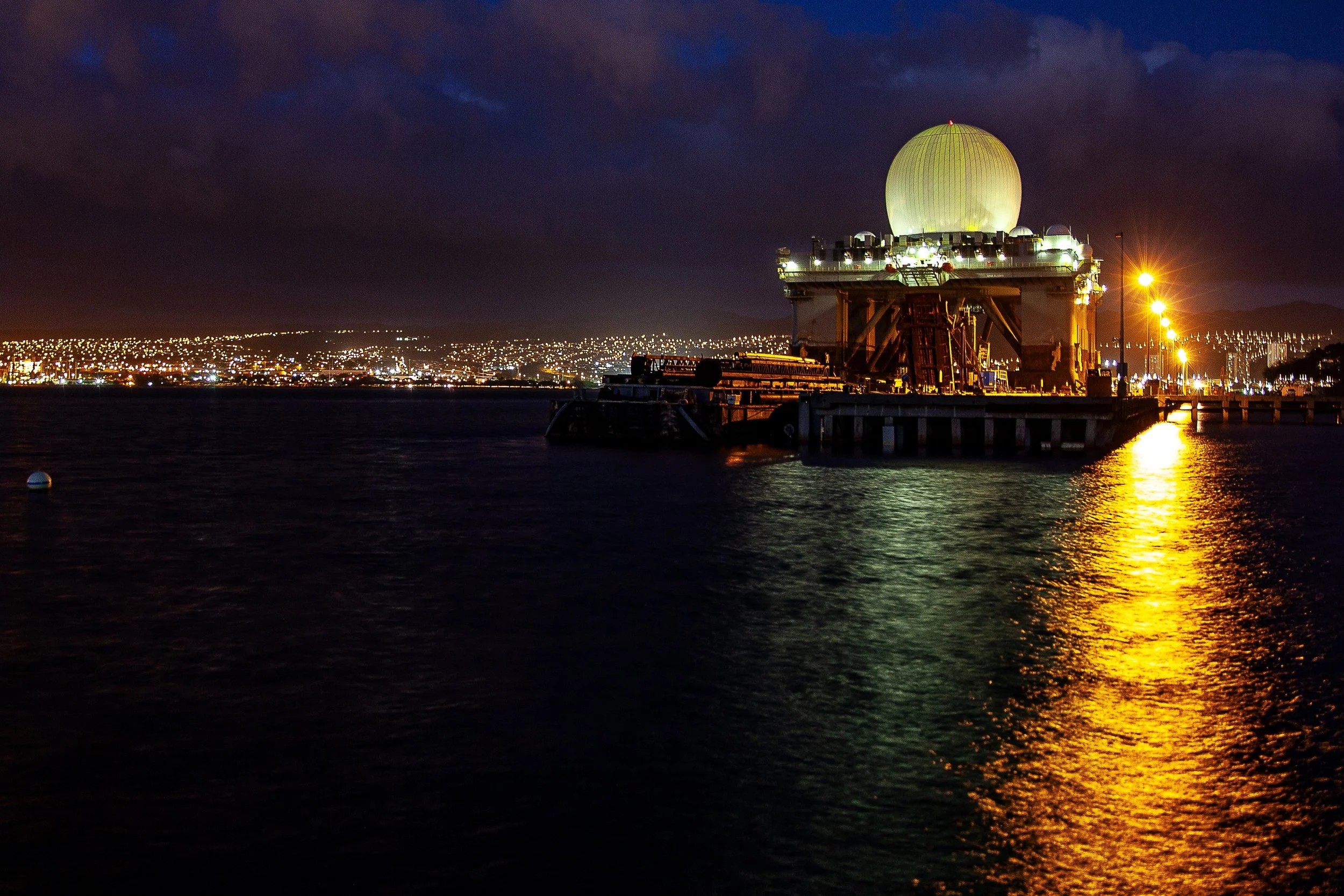Detail crop from Night Beacon, emphasizing smaller shore lights and cloud color become visible around the dominant reflection