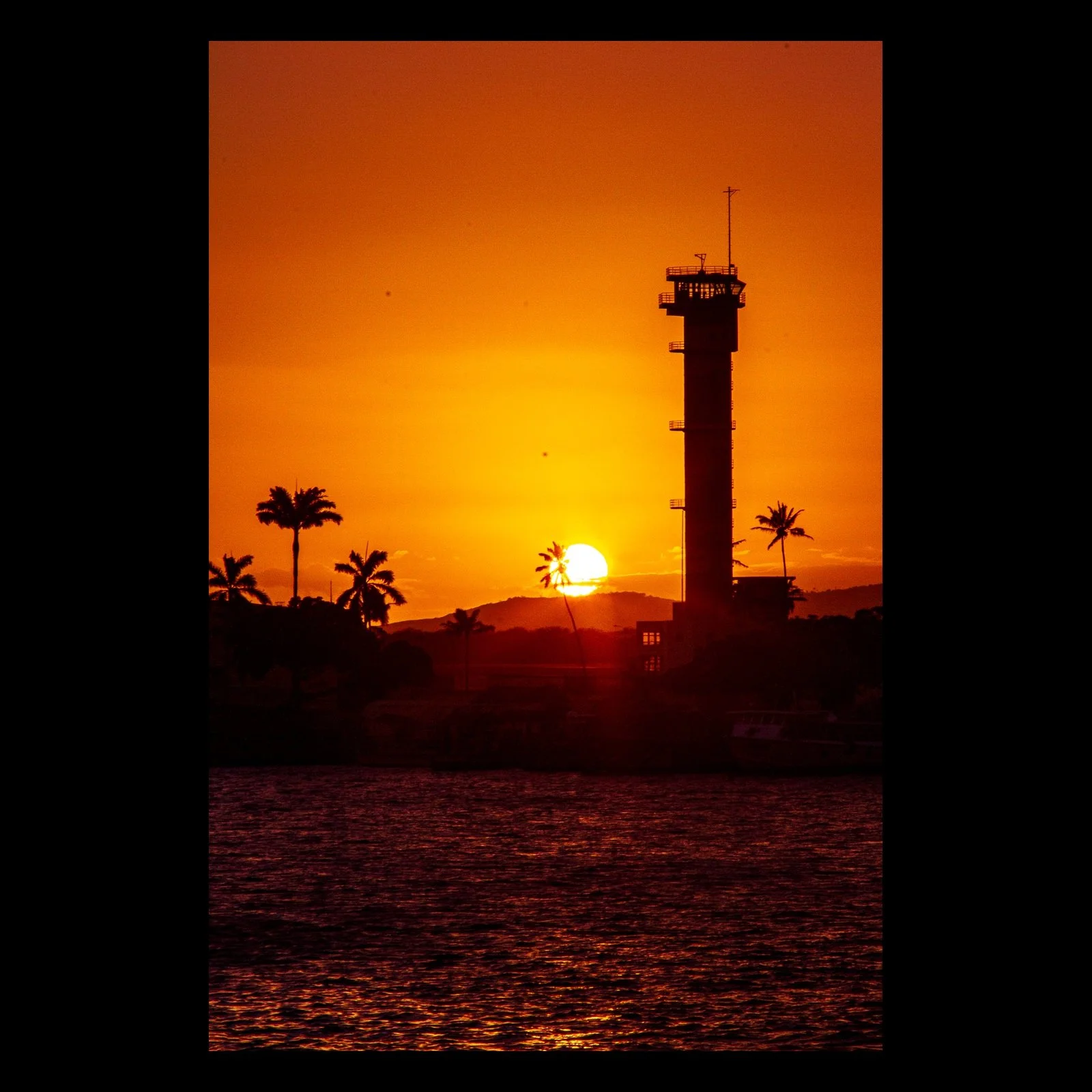 Full-frame black presentation thumbnail of Last Watch, showing the sun sets beside a silhouetted harbor tower and palms in a narrow vertical composition