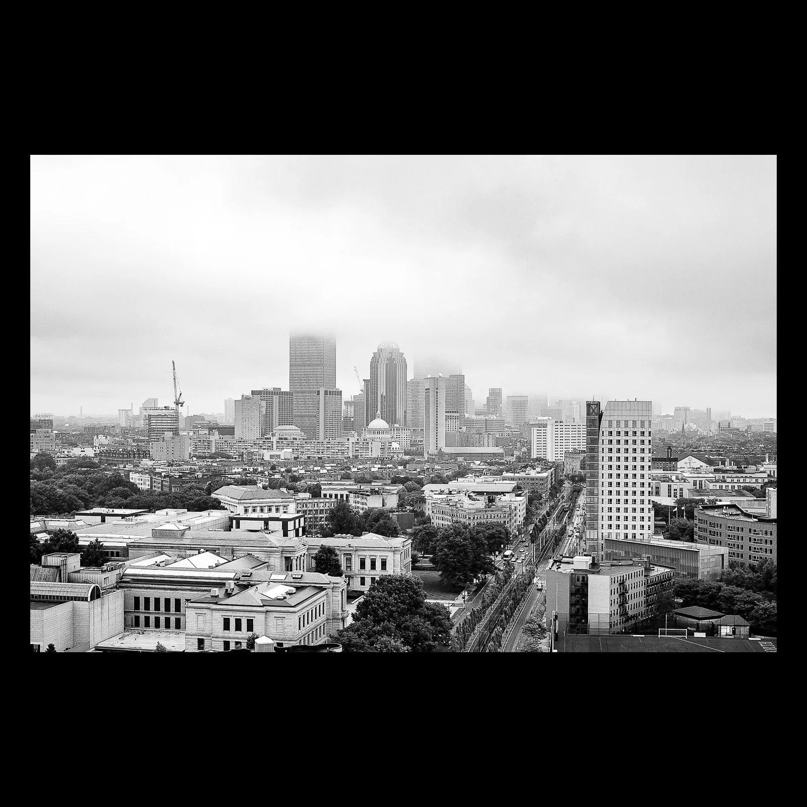 Full-frame black presentation thumbnail of City in Gray, showing a city center recedes beneath low fog in a restrained black-and-white view