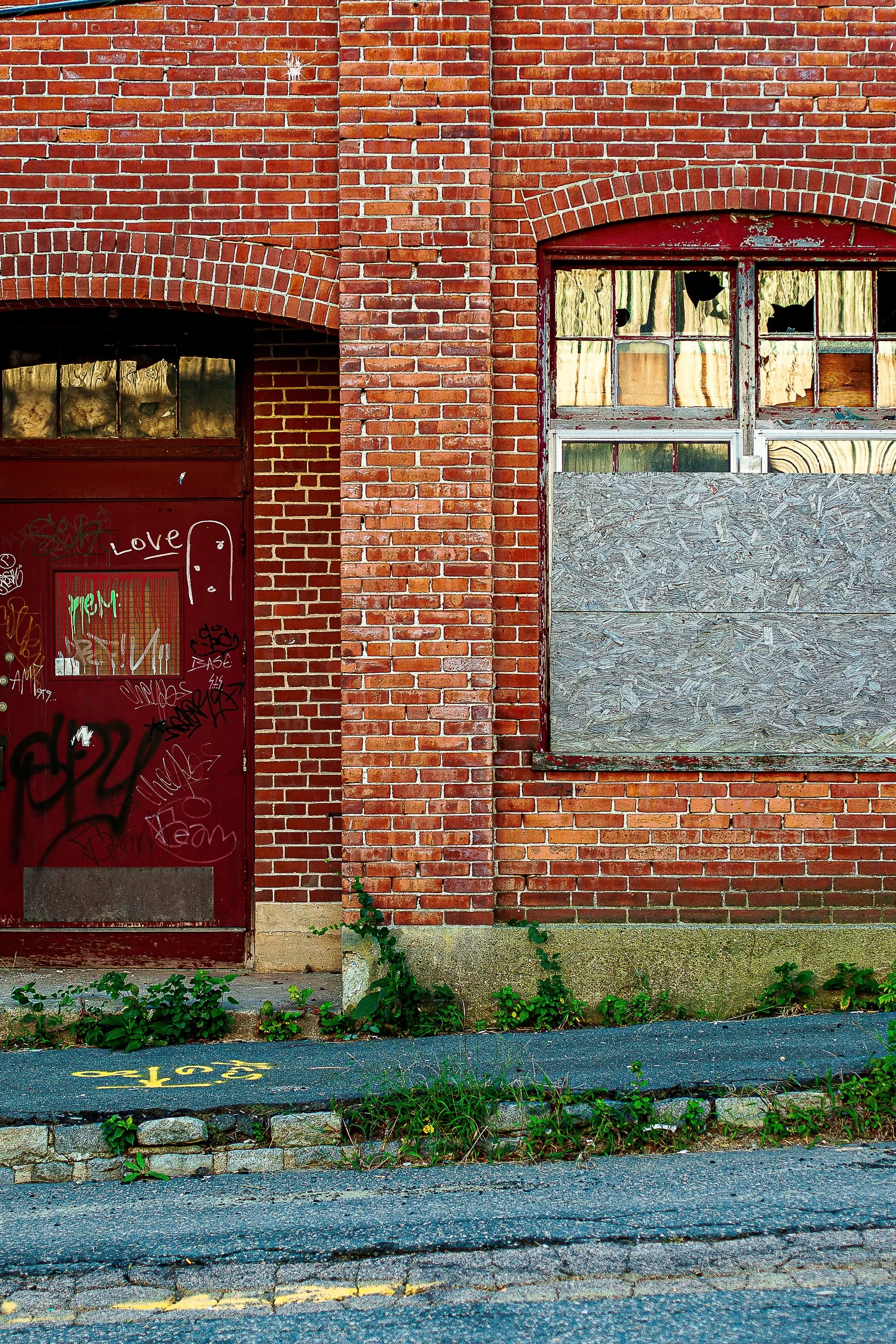 Detail crop from Tainted Love, emphasizing mortar, weeds, and mismatched openings give the wall a human history without explaining it