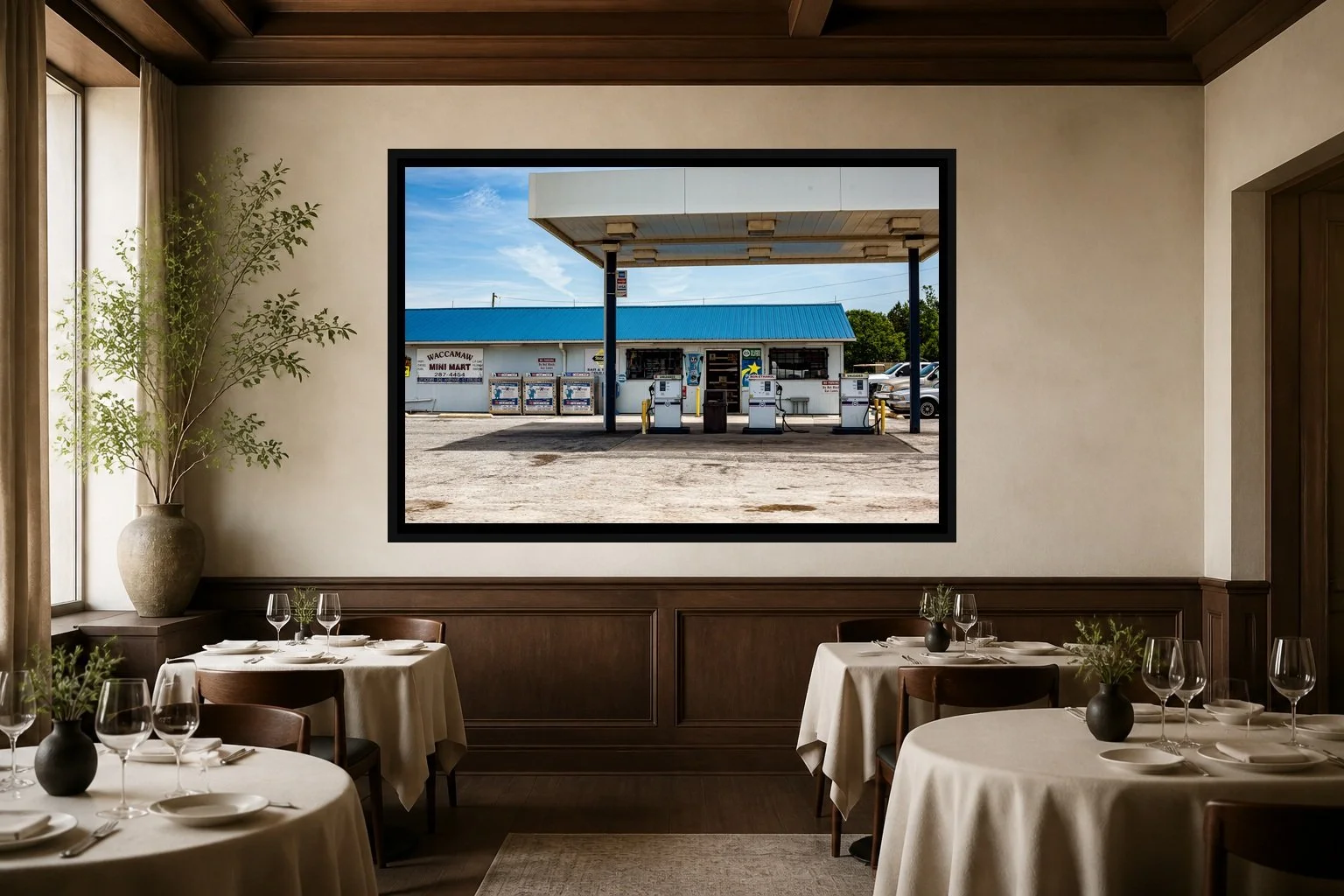 Last Fuel displayed in a black frame within an intimate fine-dining room with plaster walls, dark wood, linen tables, no guests, and a clear central wall