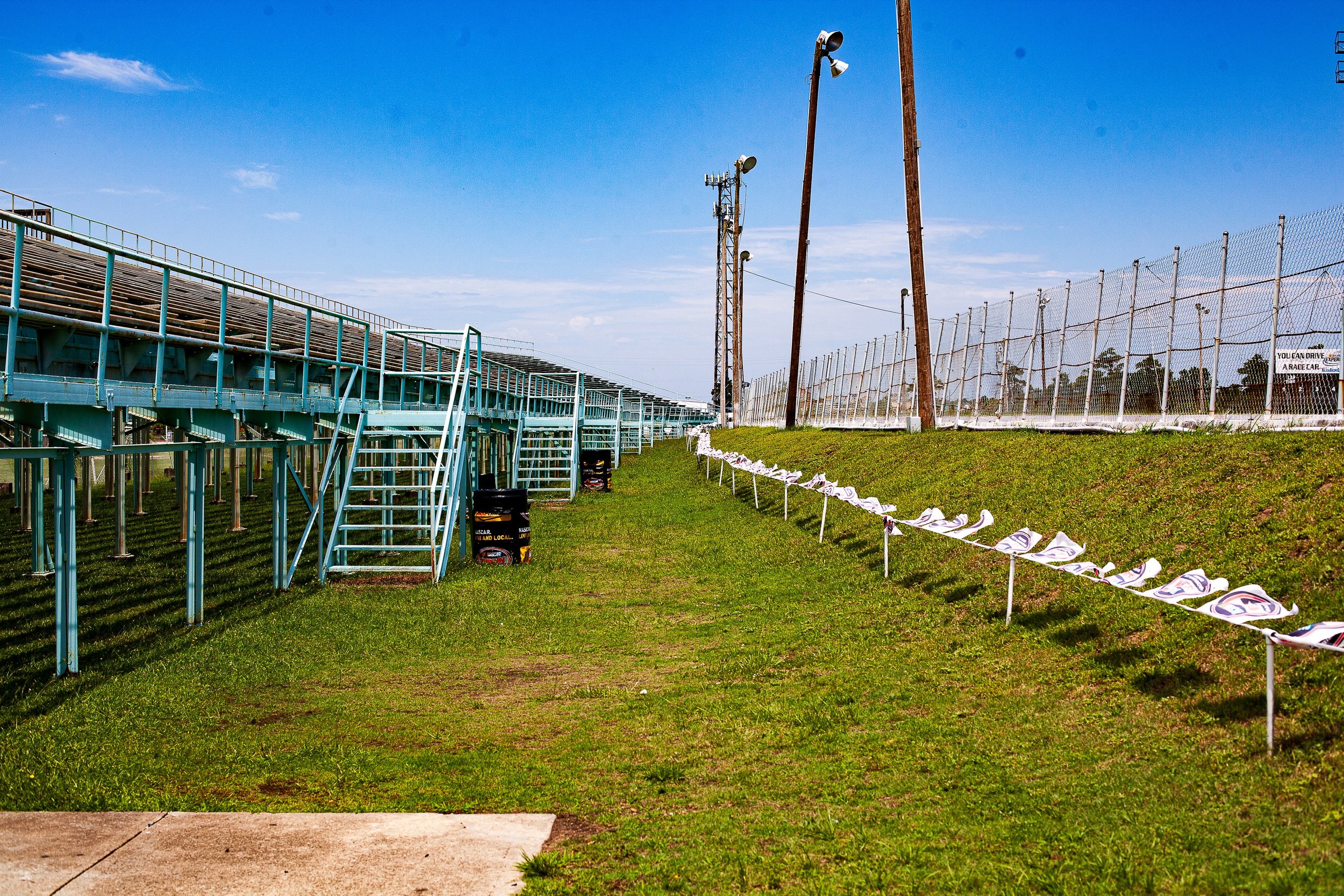Complete uncropped artwork for Grandstand After Summer, showing empty bleachers and a line of folded seats stretch beside a green field under clear sky