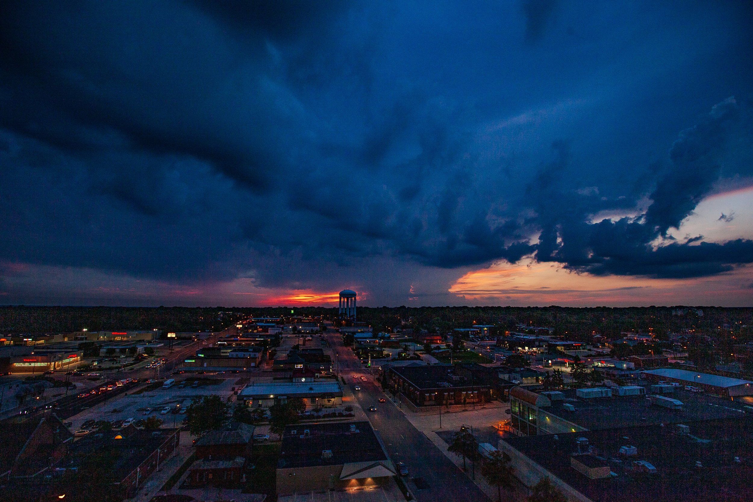 Complete uncropped artwork for Storm Over Town, showing a dark blue storm shelf advances above a town while a thin red sunset remains at the horizon