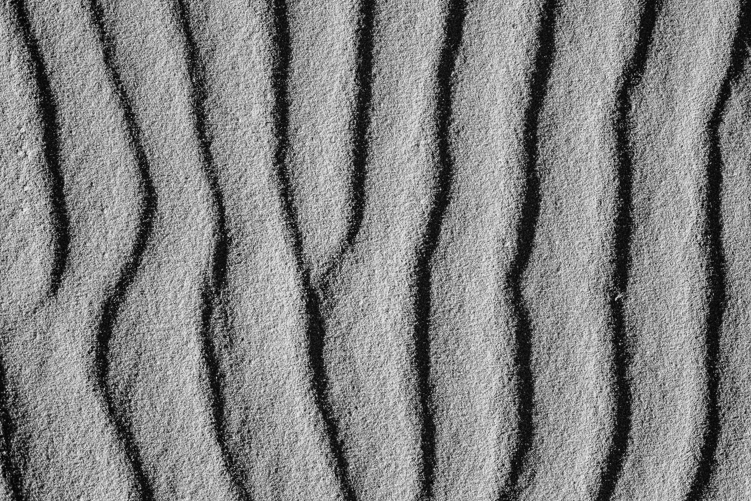 Complete uncropped artwork for Wind Written, showing fine parallel ridges run through pale sand in a tightly framed monochrome study