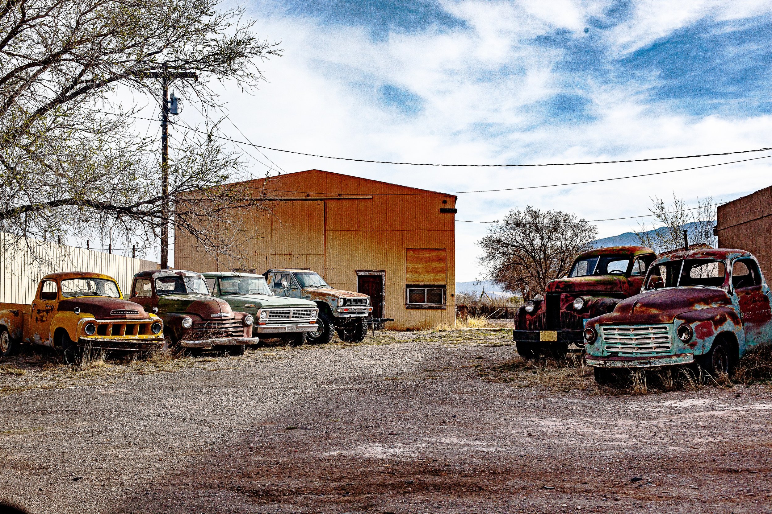 Complete uncropped artwork for Working Relics, showing a row of weathered trucks waits outside an industrial building under winter light