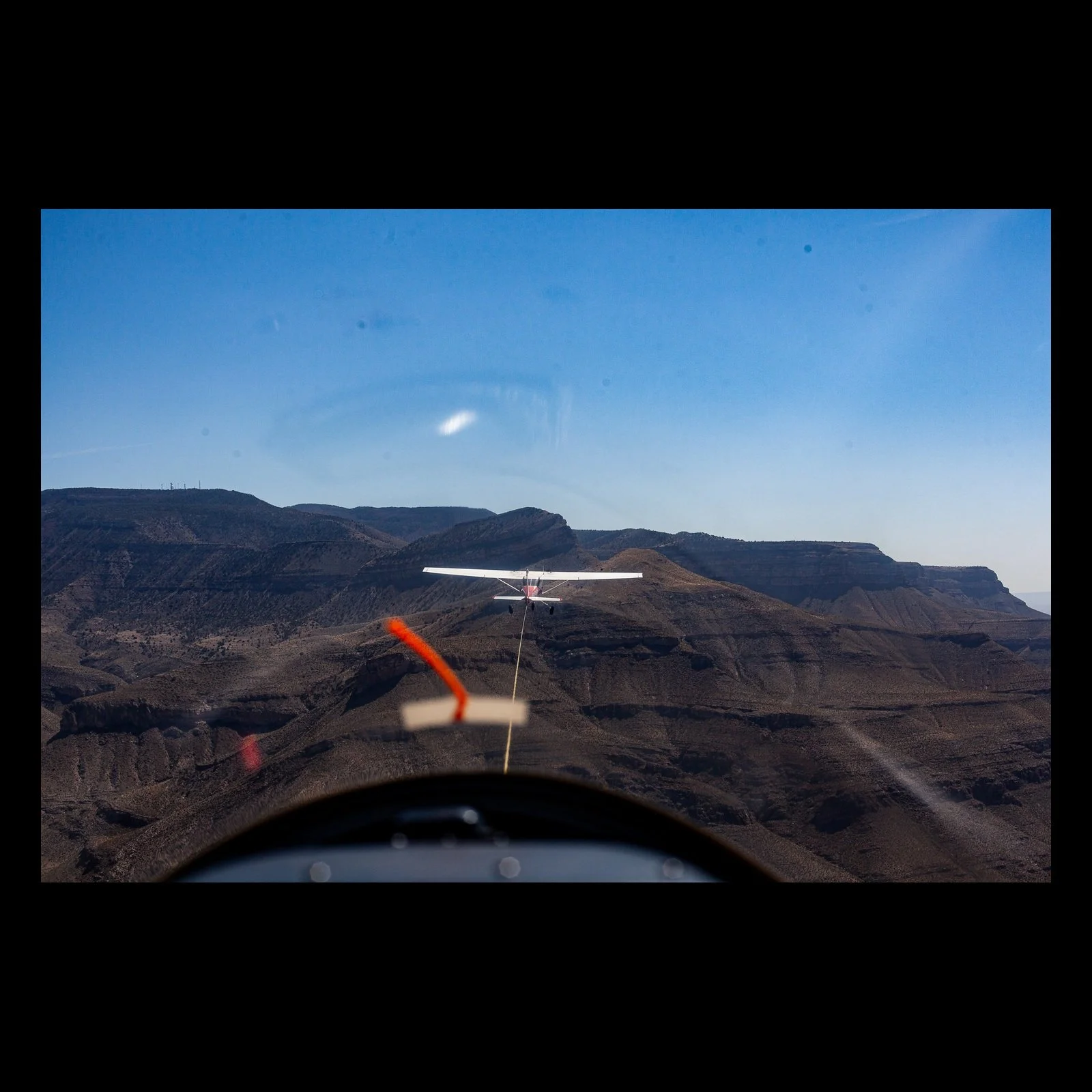 Full-frame black presentation thumbnail of Final Approach, showing a small airplane aligns with a runway beyond the cockpit of another aircraft