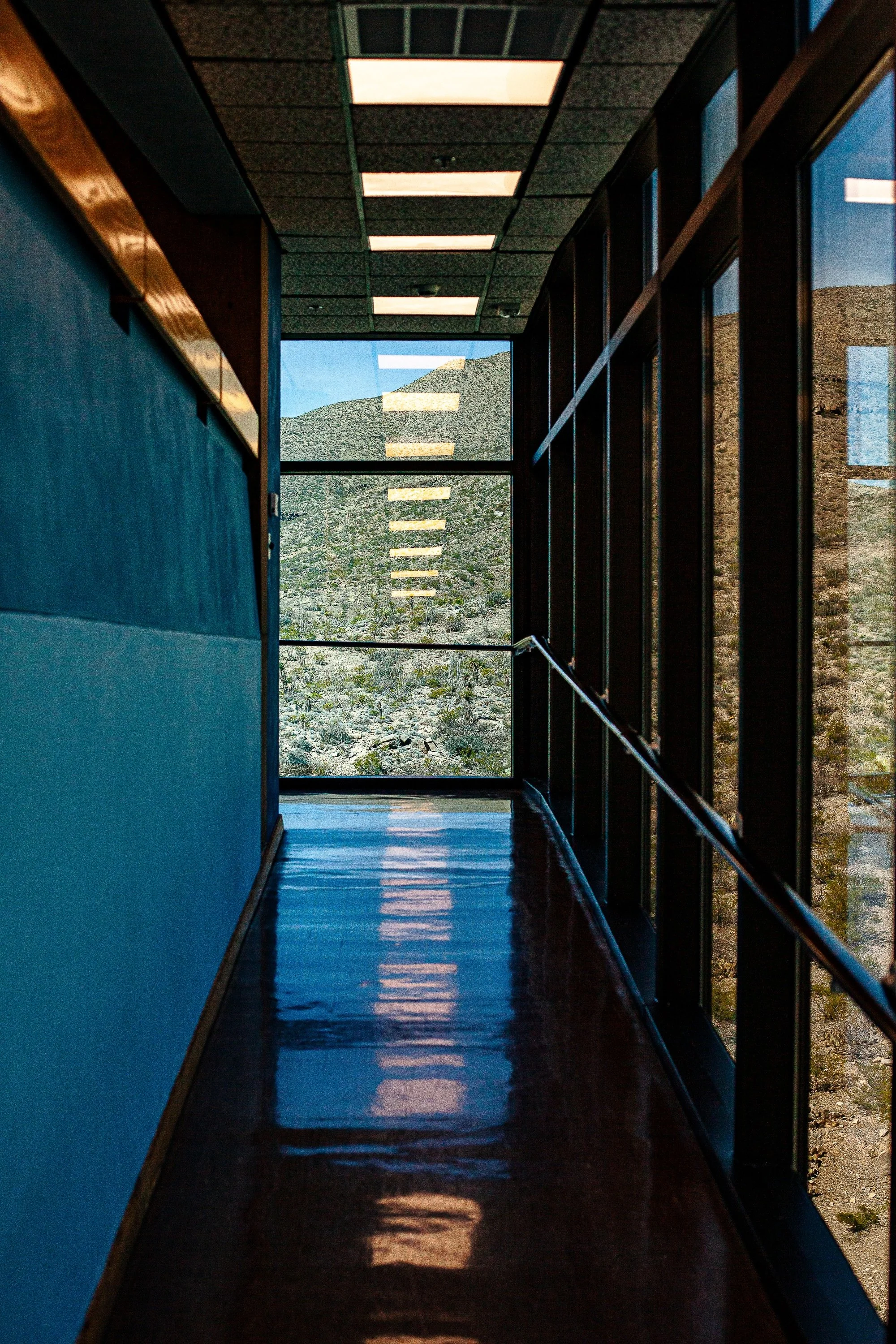 Complete uncropped artwork for Corridor in Blue, showing a narrow blue corridor leads through repeating windows toward a bright exterior opening
