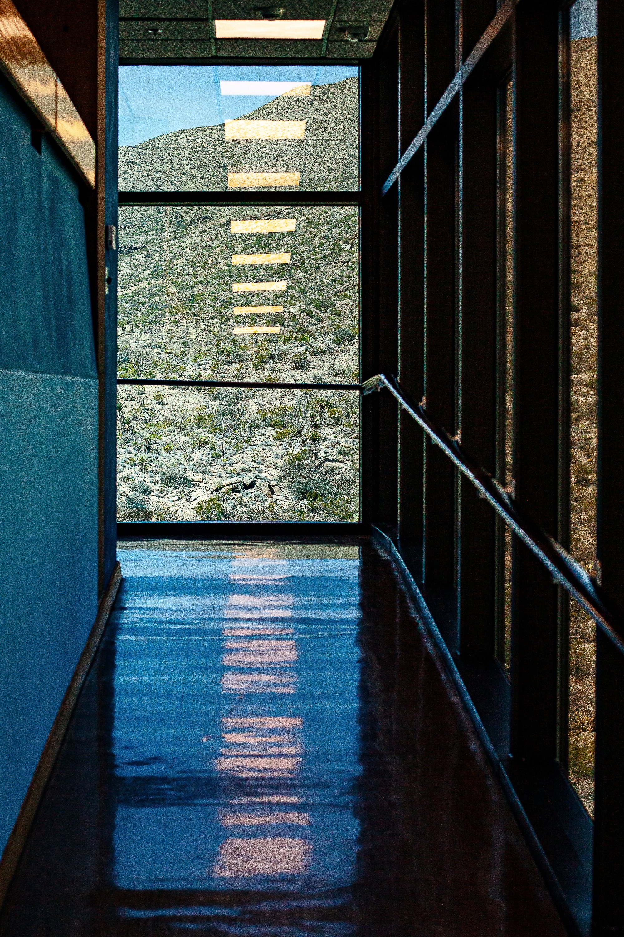 Detail crop from Corridor in Blue, emphasizing ceiling lights and dark mullions create a measured rhythm toward the far end