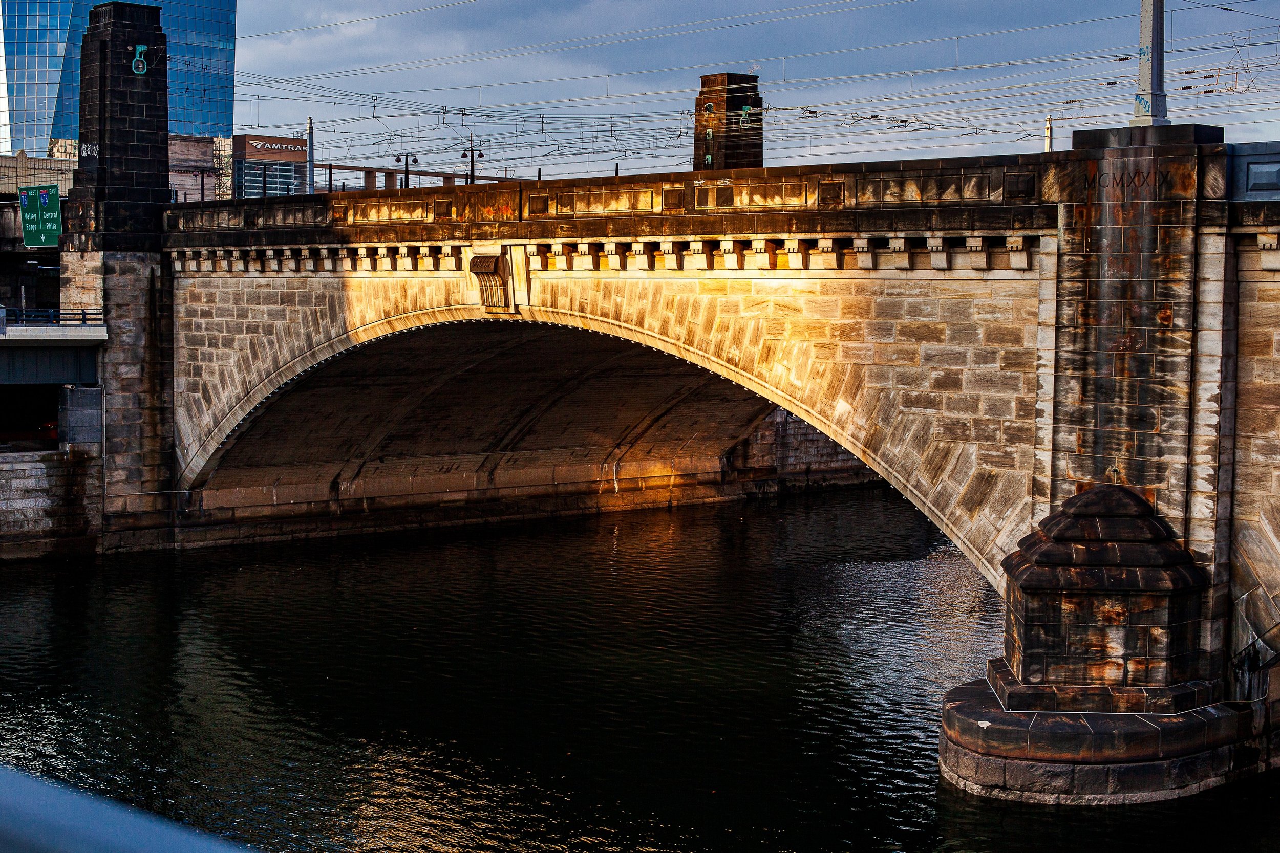 Complete uncropped artwork for Stone Crossing, showing warm late light traces an old stone bridge reflected in dark river water