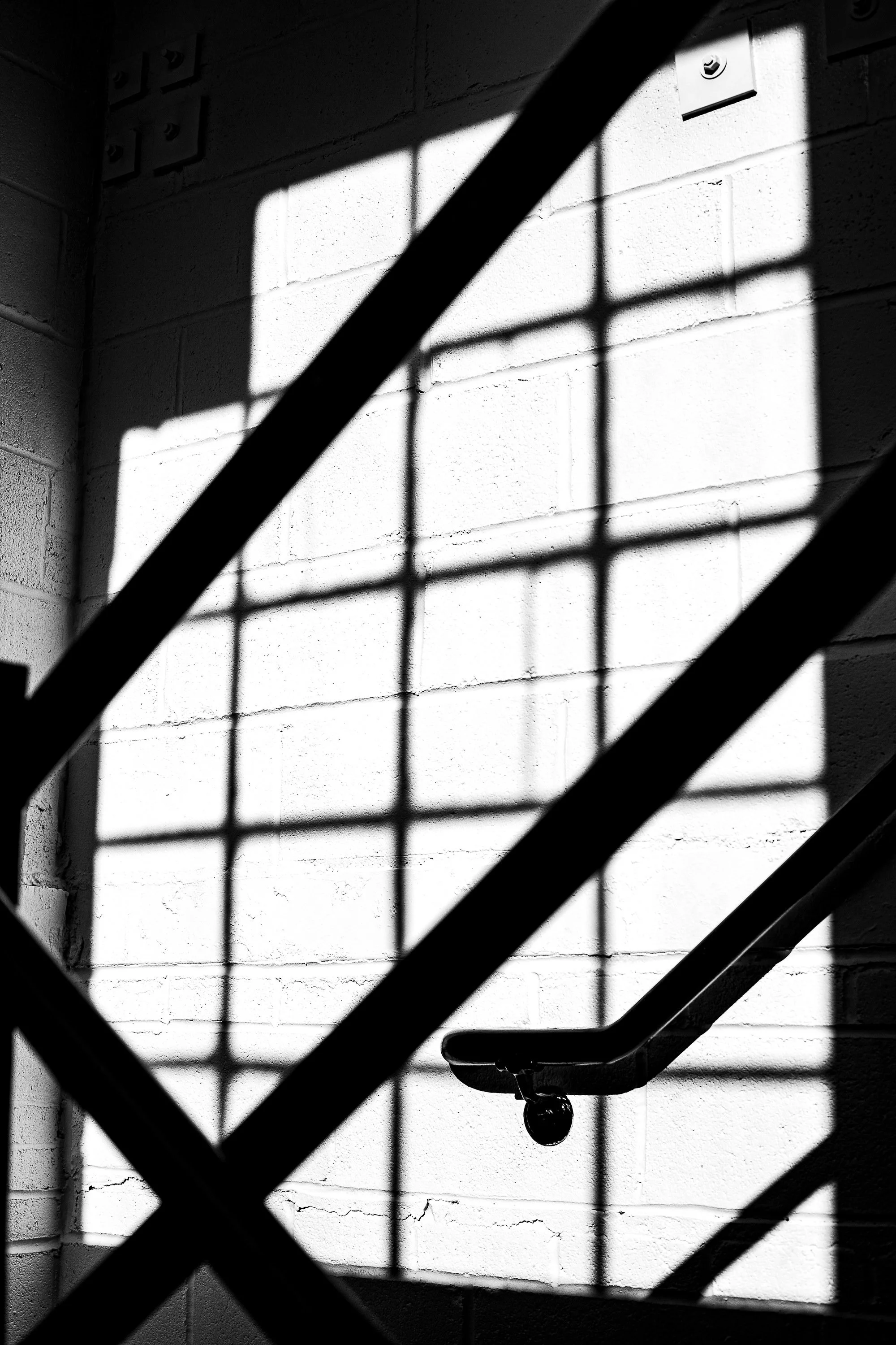 Complete uncropped artwork for Shadow Rail, showing a diagonal handrail and structural shadows cut across a bright industrial window in black and white