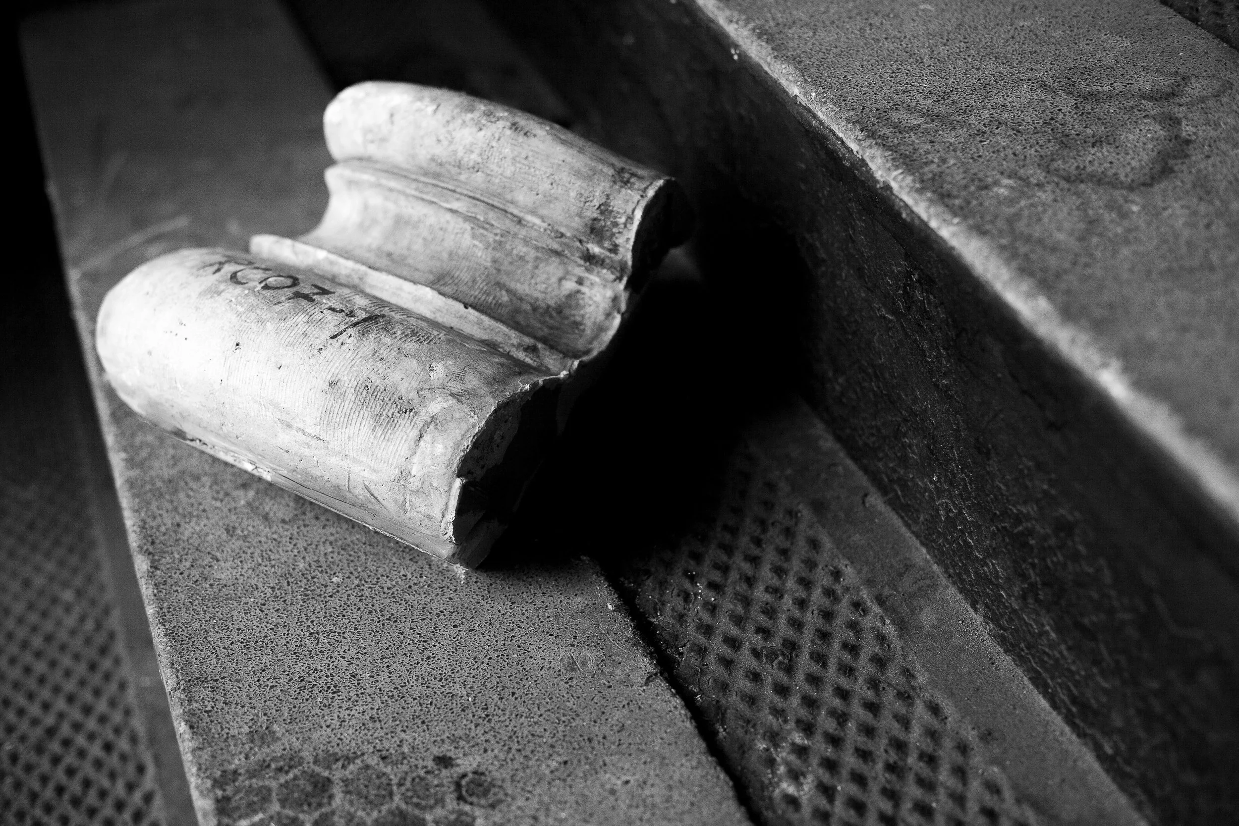 Complete uncropped artwork for Fallen Fragment, showing a damaged pale architectural fragment rests on a dark industrial ledge in black and white