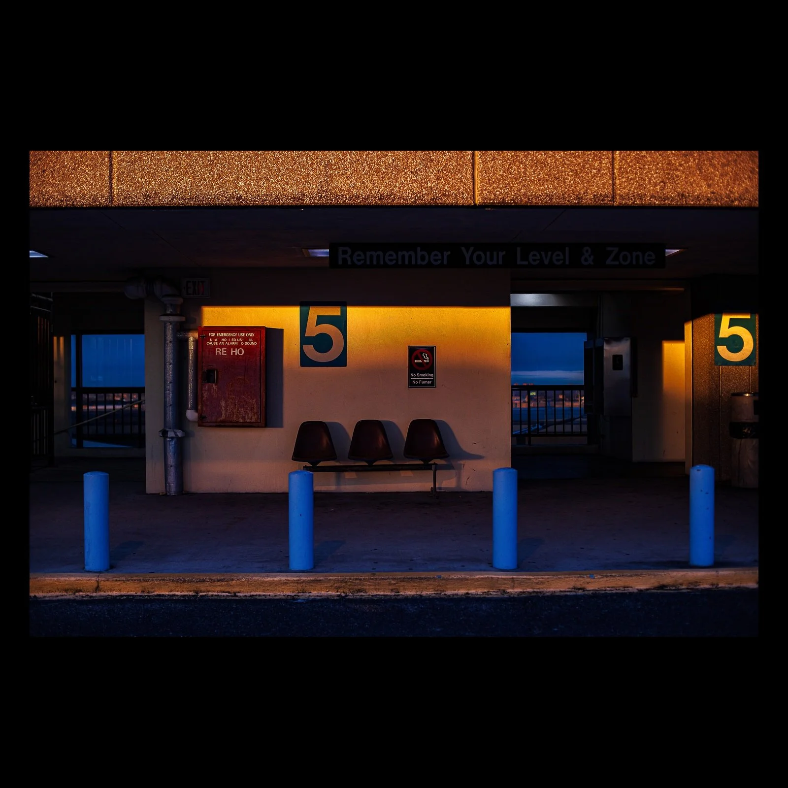 Full-frame black presentation thumbnail of Remember Level Five, showing an empty parking level glows blue and amber around a large numeral five
