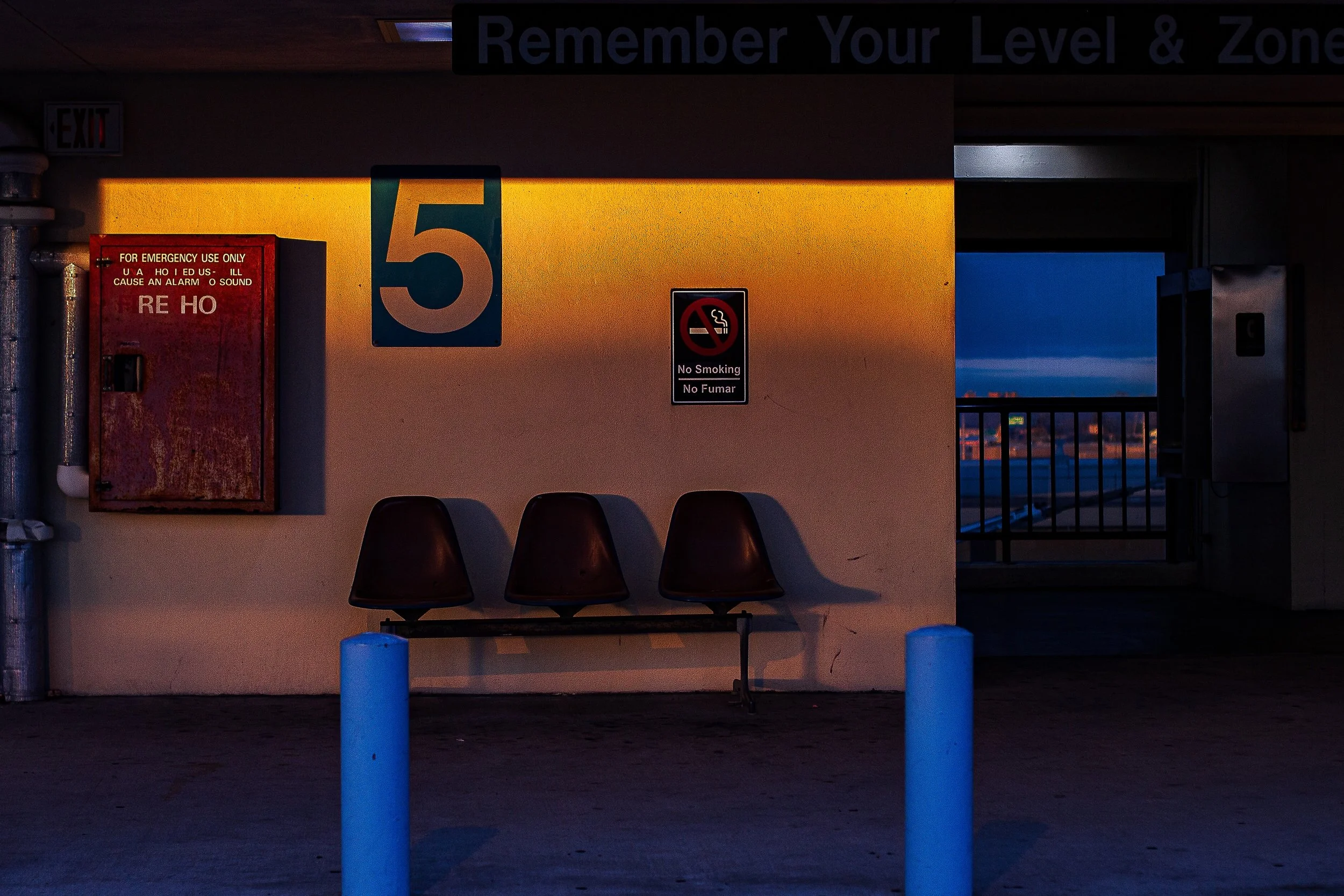 Detail crop from Remember Level Five, emphasizing chairs, bollards, and signage hint at waiting without revealing for whom